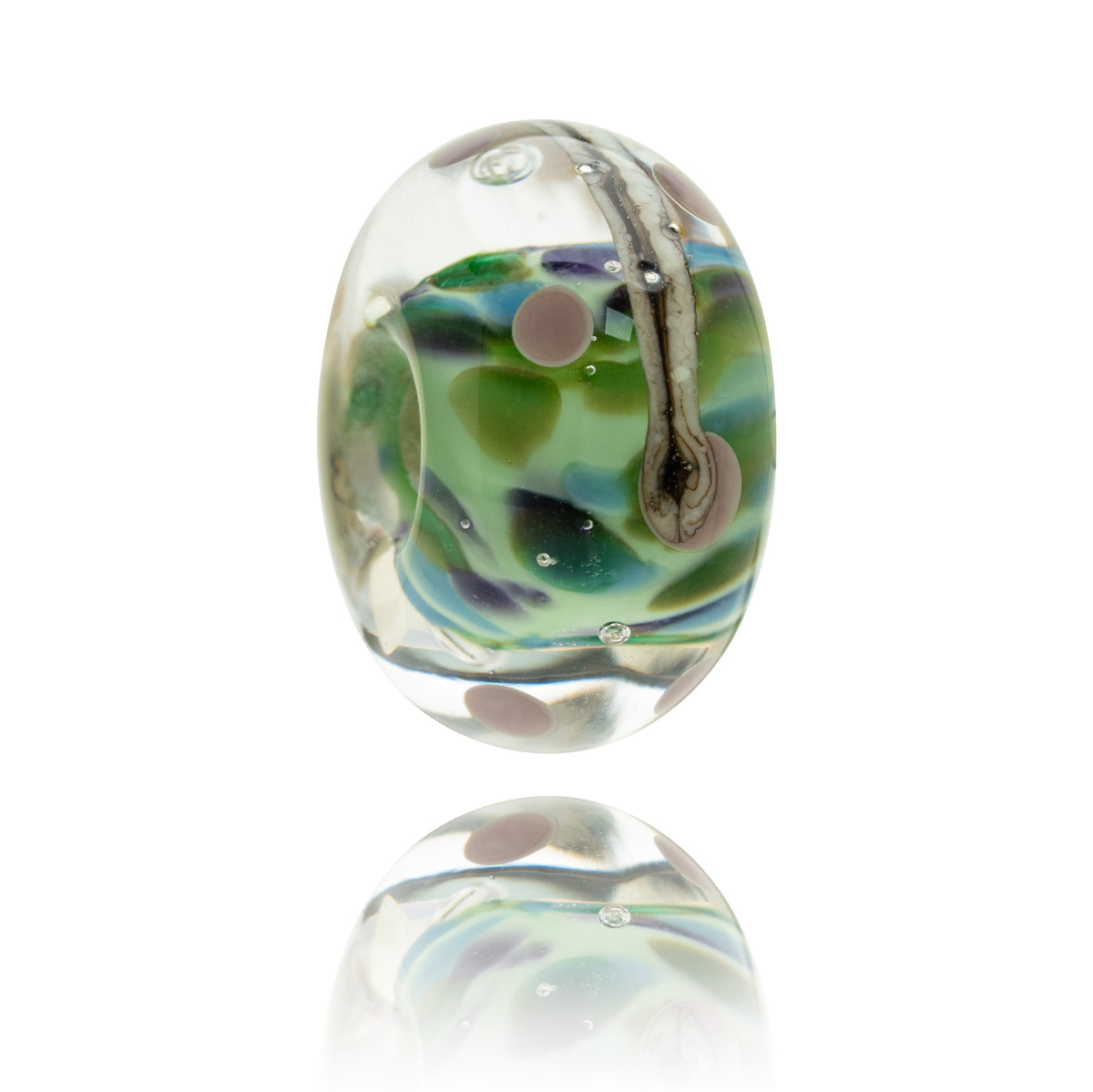 A single oval glass lampwork bead with a clear base and swirls of green, blue, and lavender, featuring a small bubble and a light brown loop detail, shown on a white background with a soft reflection below.