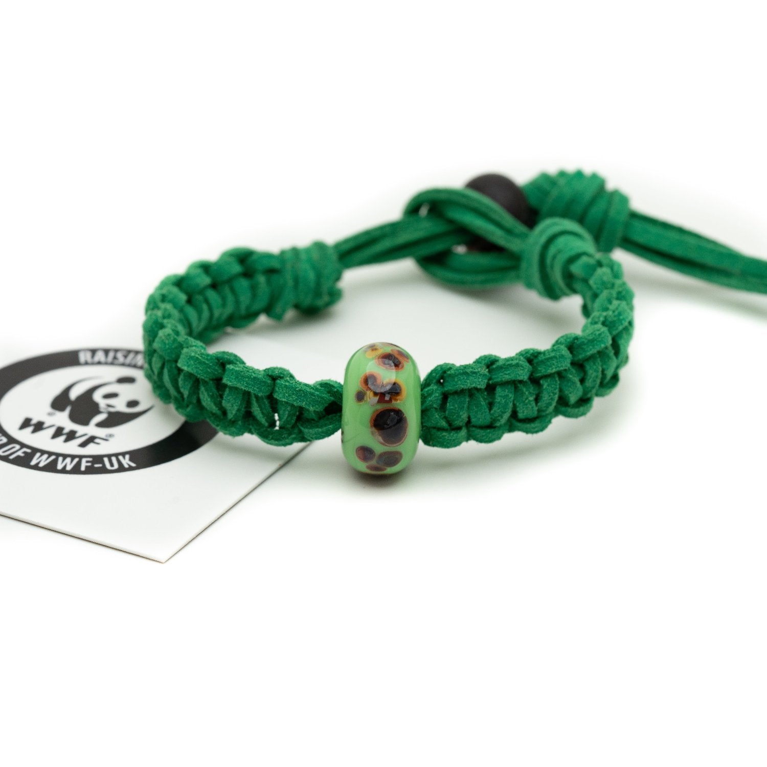 A green glass bead bracelet with brown spots on the surface being sold to raise funds for the World Wildlife Foundation.