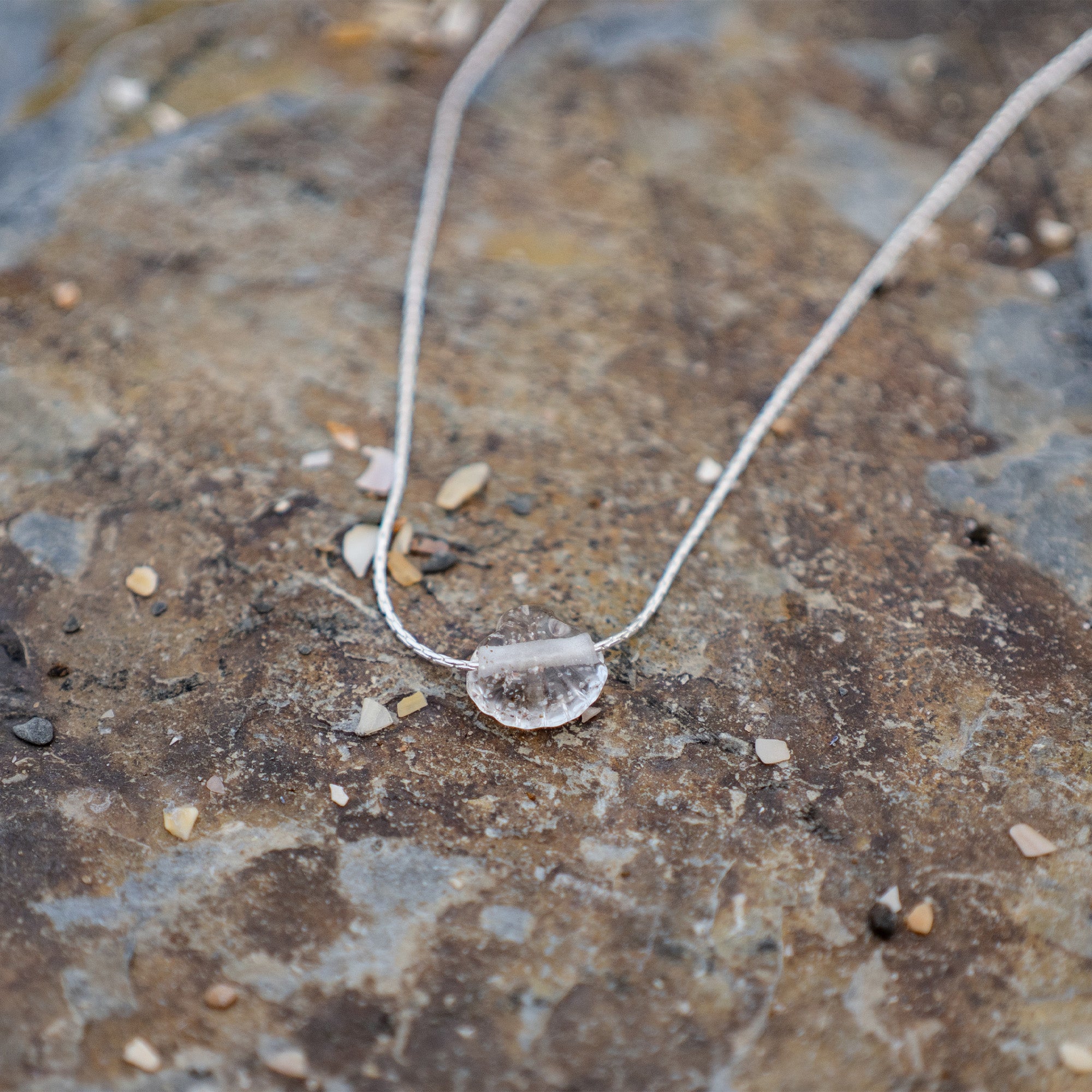 Necklace with a clear pendant on a textured stone surface