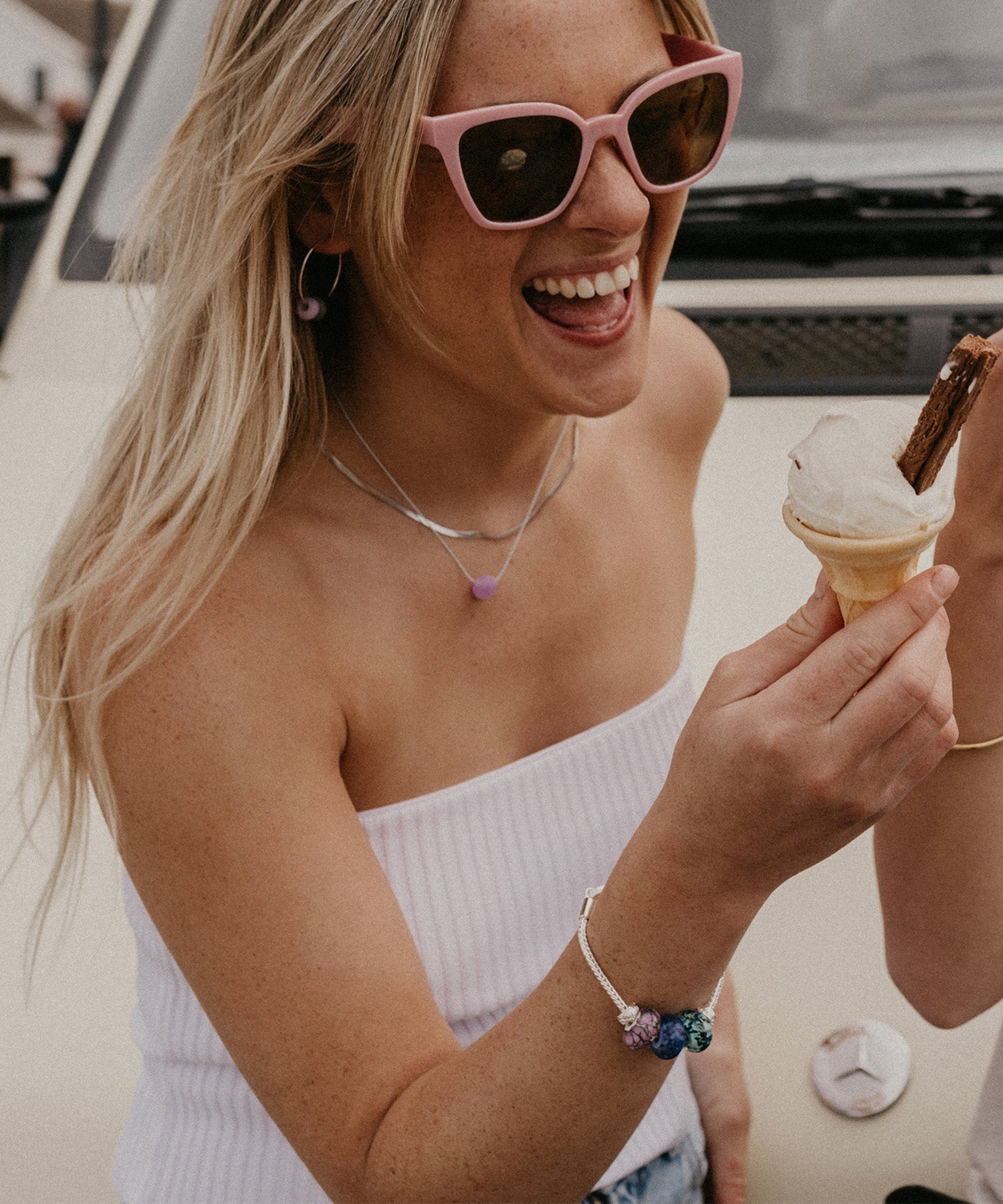 Silver jewellery, bracelets and necklaces on girl eating ice cream.