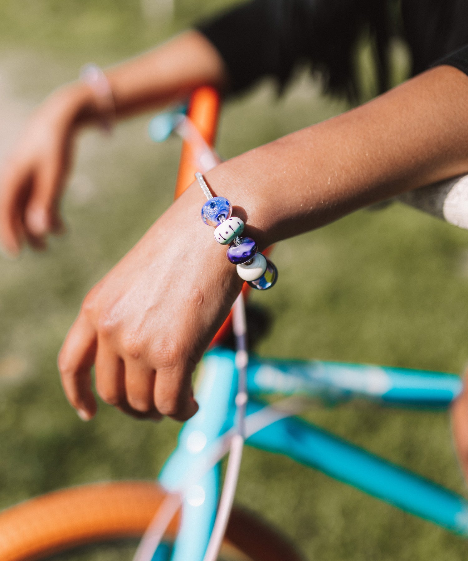 Colourful glass beads worn on sterling silver bracelet by girl on BMX bike.