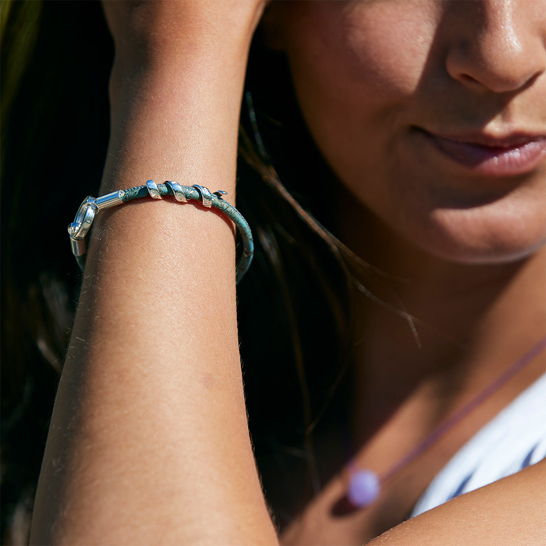 Woman wearing a teal leather bracelet with silver findings.