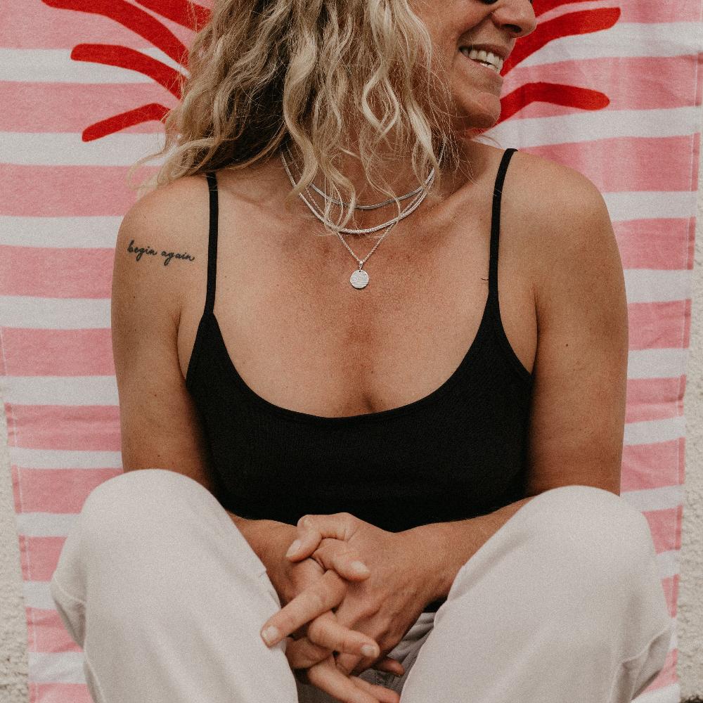 Woman wearing silver necklace layers and silver Nalu talisman charm.