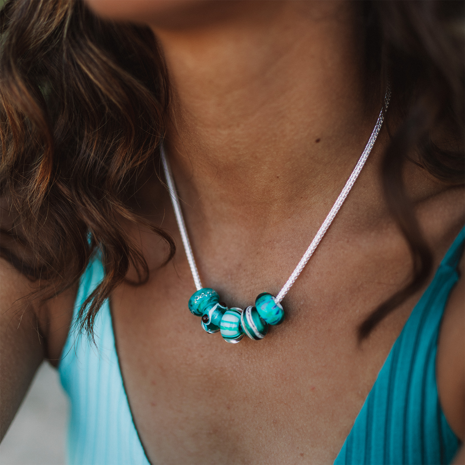 Woman wearing silver chain necklace with green glass beach inspired beads.