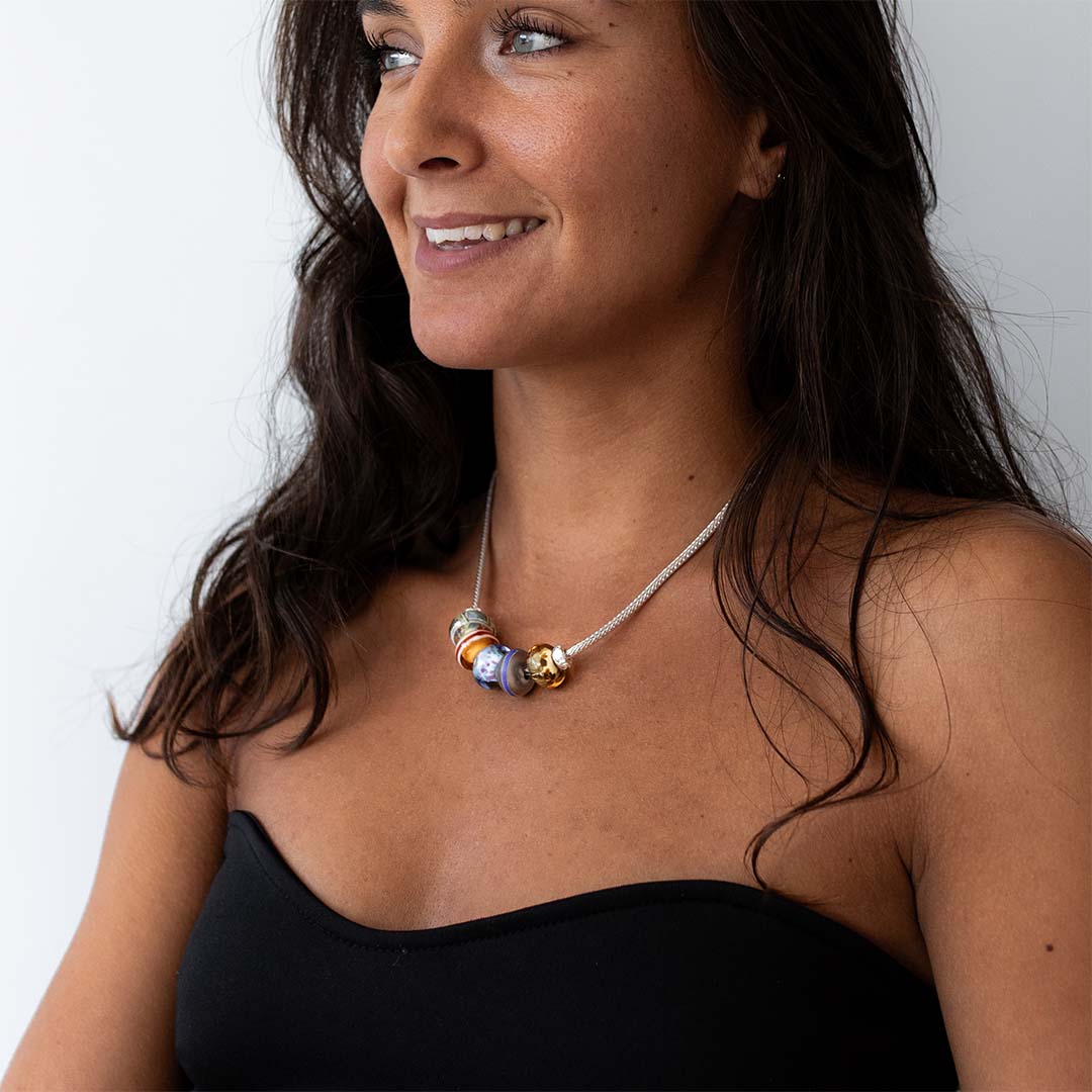 Dark haired woman wearing chunky silver necklace with coloured Murano glass beads.