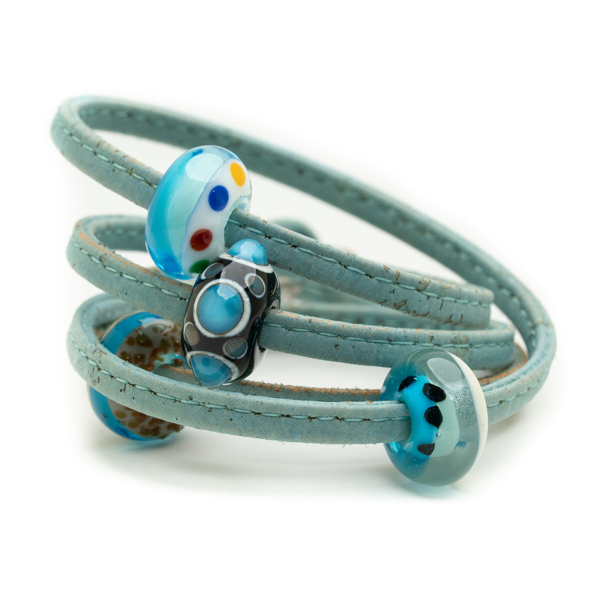 A light blue wrap bracelet with three coiled bands and decorative glass beads, including a blue and white bead with colorful dots, a black and blue patterned bead, and a blue bead with black spots, on a white background.