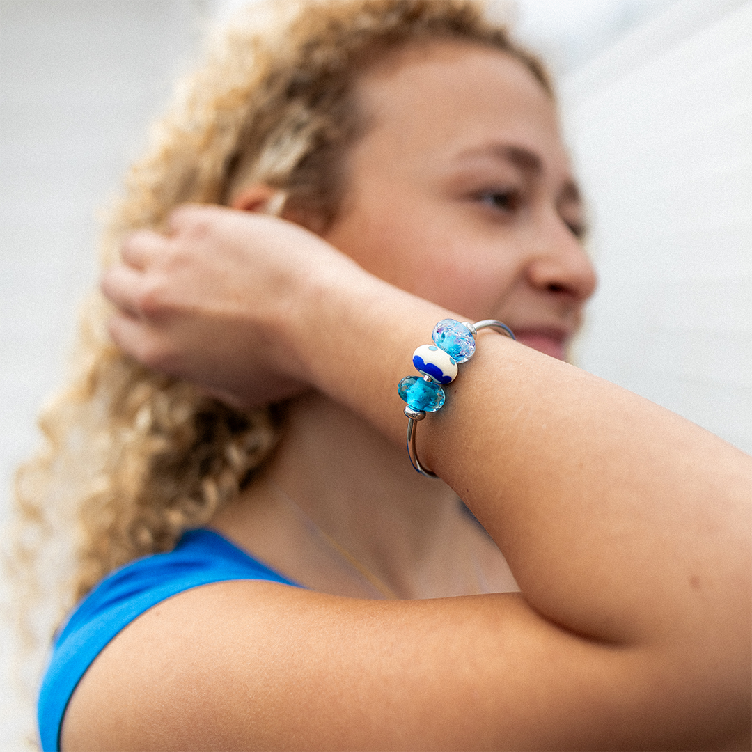 Girl wearing silver bangle with blue glass surf beads.