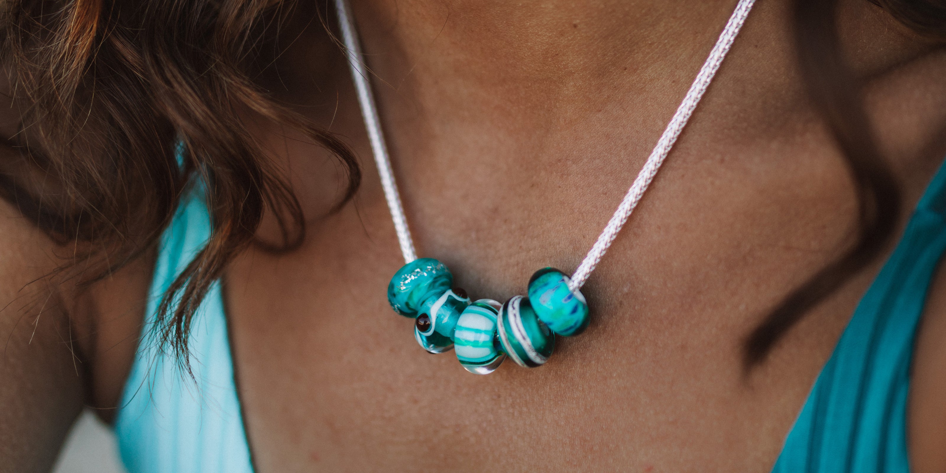 Green and turquoise surf inspired beads worn on silver dragon chain necklace by dark hair lady.