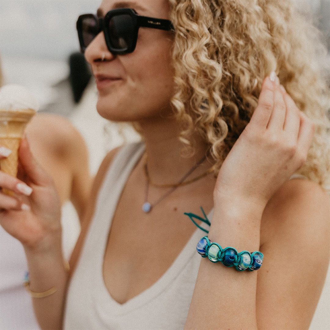 Girl eating an ice cream wearing a teal cord bracelet with swirling glass beads.