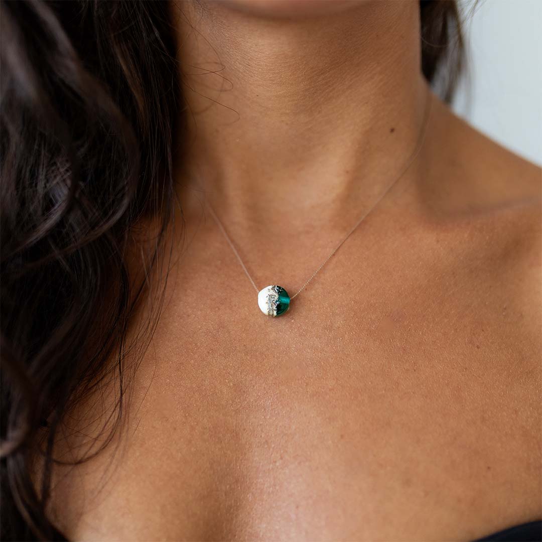 Dark haired woman wearing a silk necklace with teal and sand glass pendant.