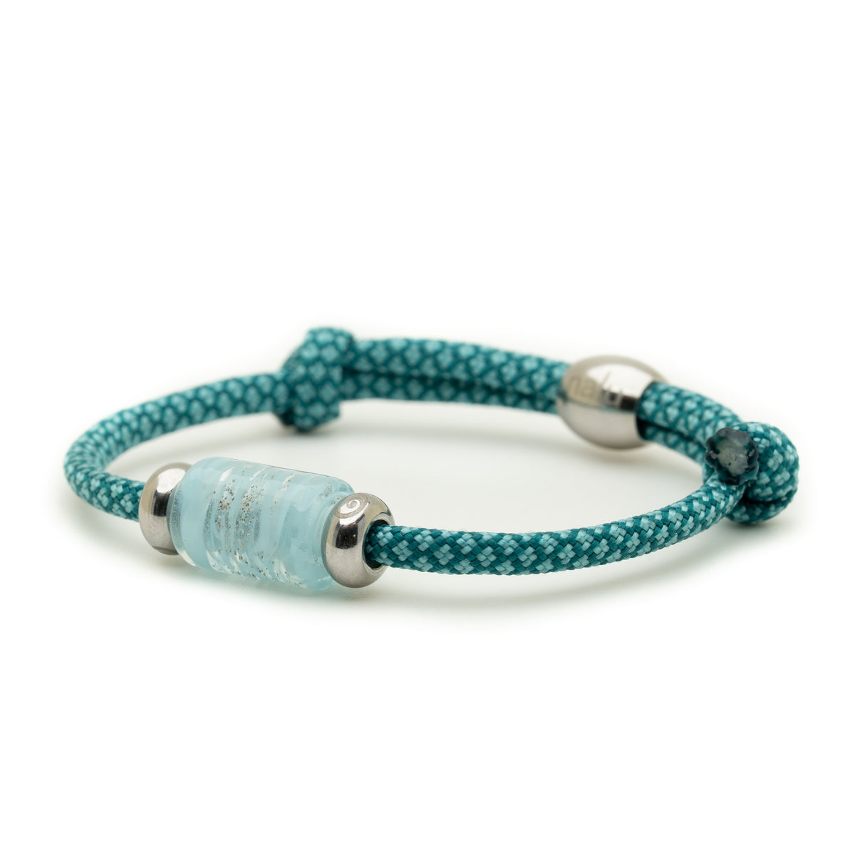 A teal and white patterned cord bracelet with a light blue cylindrical bead and silver metal caps, shown on a plain white background.