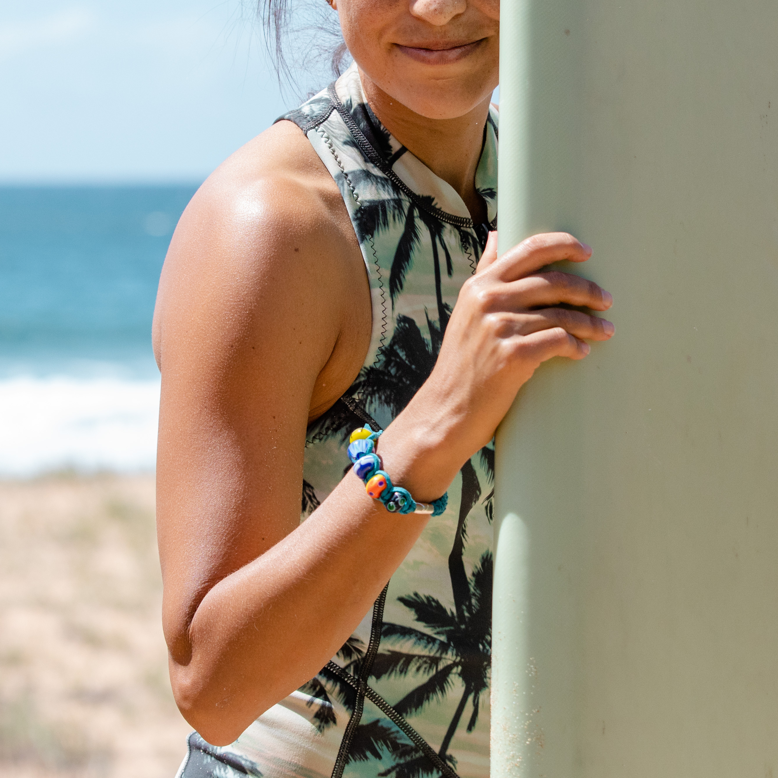 Surfer wearing custom bracelet with coloured glass beads strung on.