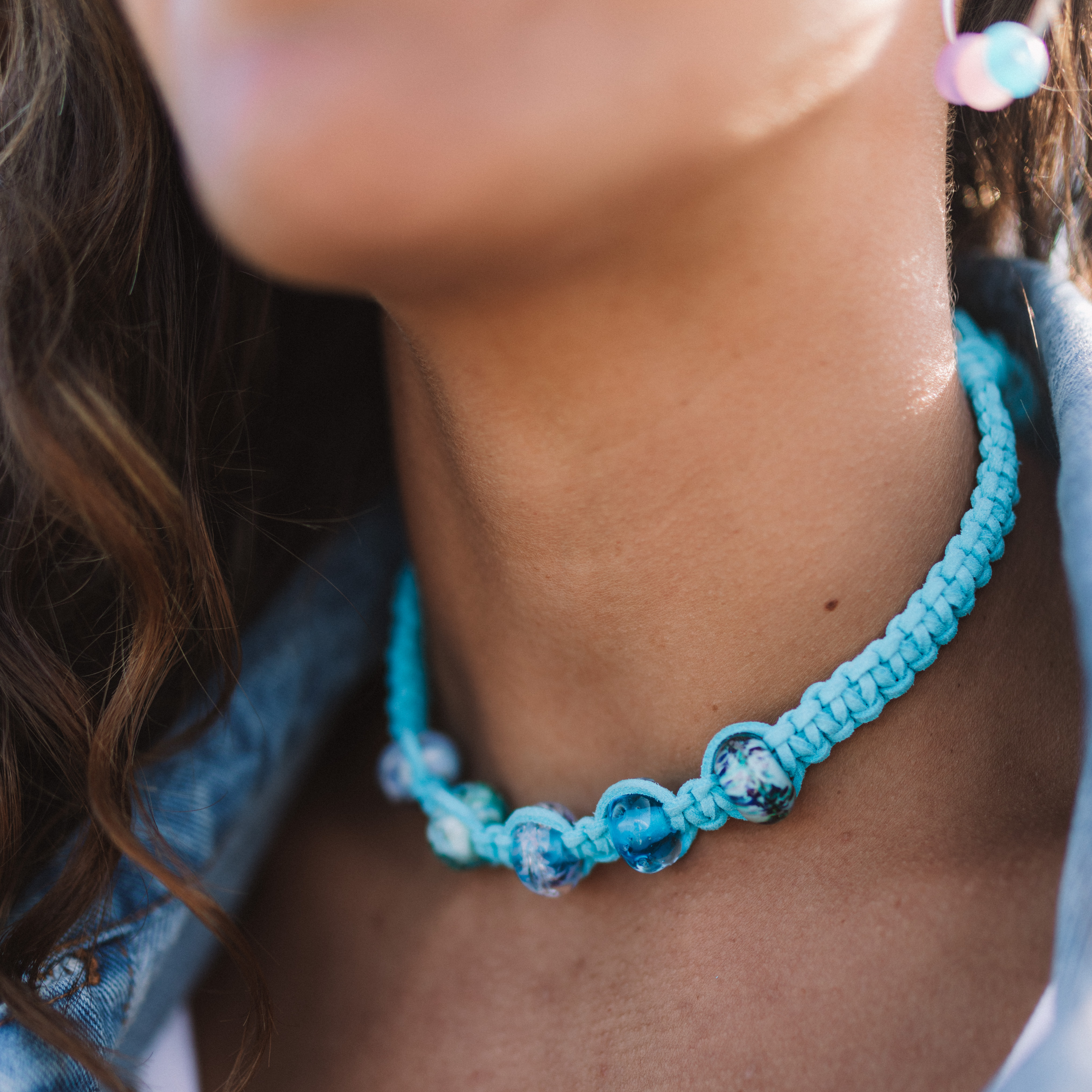 turquoise cord choker necklace with glass beads worn by woman.