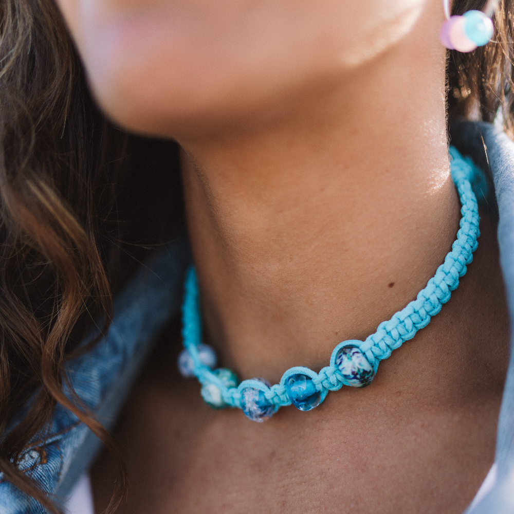 Woman wearing turquoise macrame cord choker necklace with blue, purple Murano glass beads.