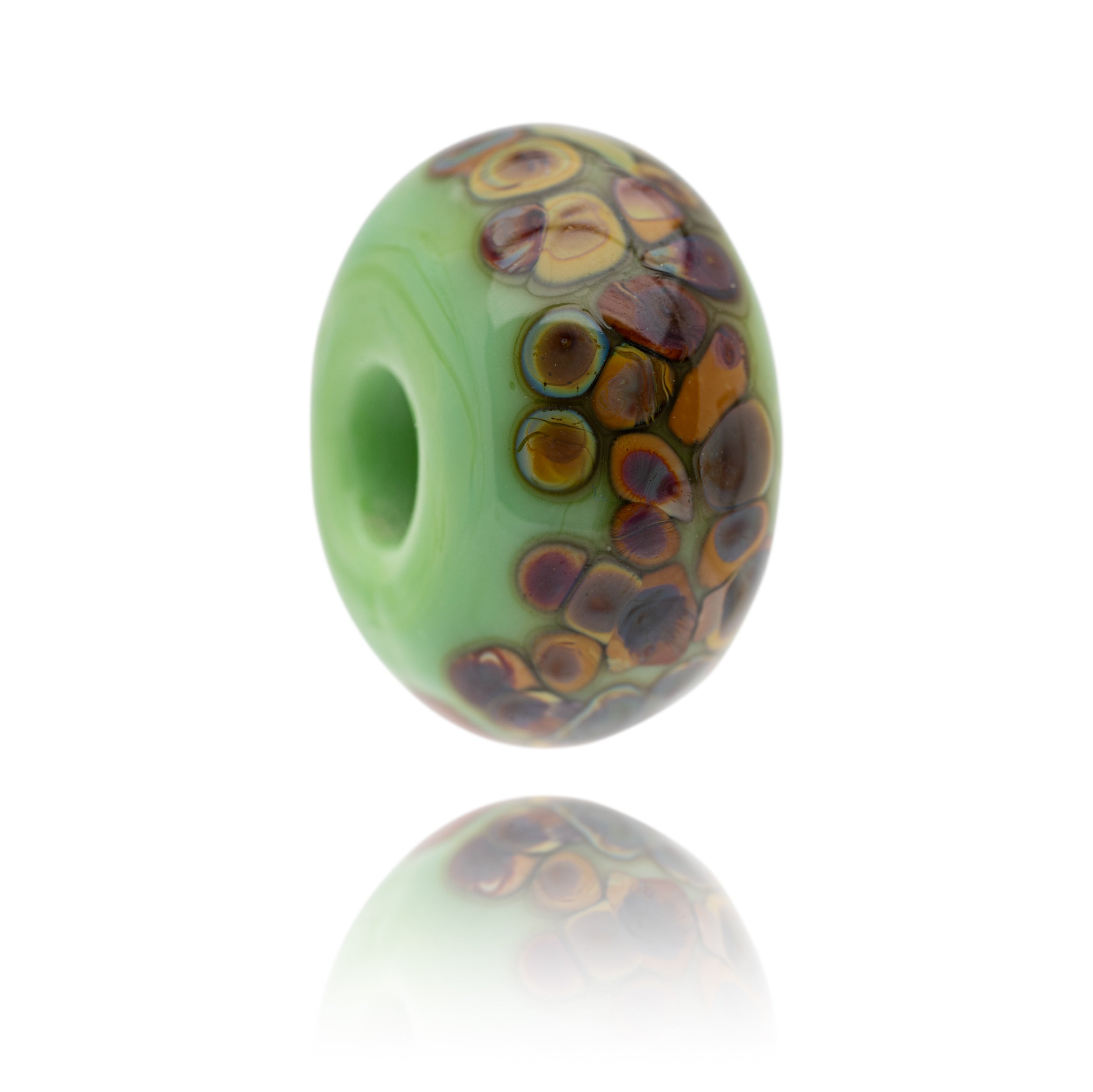 A green glass bead with brown spots on the surface being sold to raise funds for the World Wildlife Foundation.