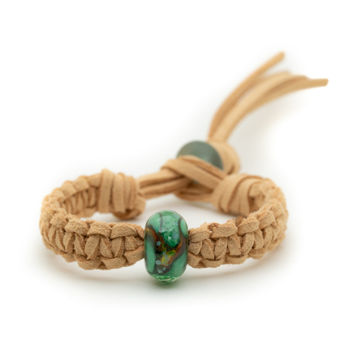 A tan braided cord bracelet with a prominent green marbled bead and a smaller green accent bead, photographed on a clean white background.