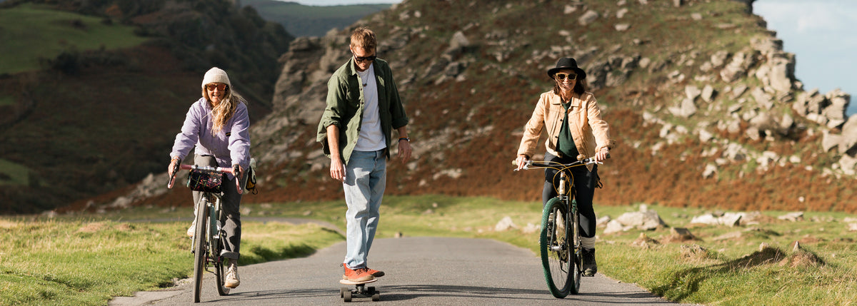 Three people riding bikes and skateboards through the Valley Of The Rocks in North Devon, Exmoor.