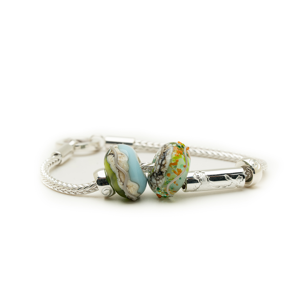 Silver bracelet with two colorful beads on a white background