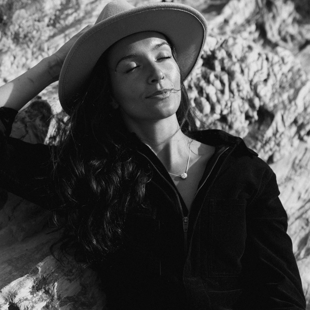 Woman in black and white photo wearing a hat and necklace.
