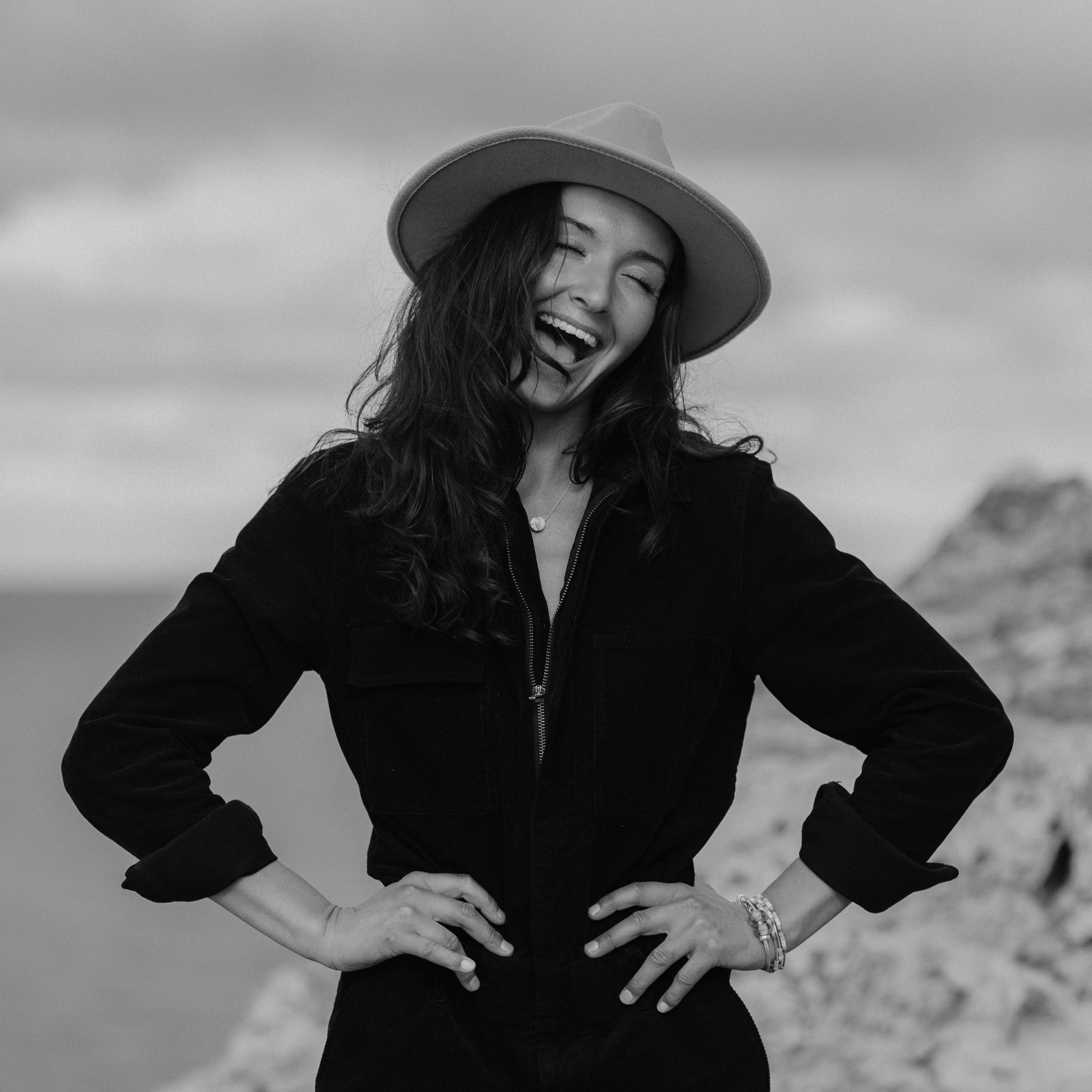 Woman wearing a hat on craggy cliff point.