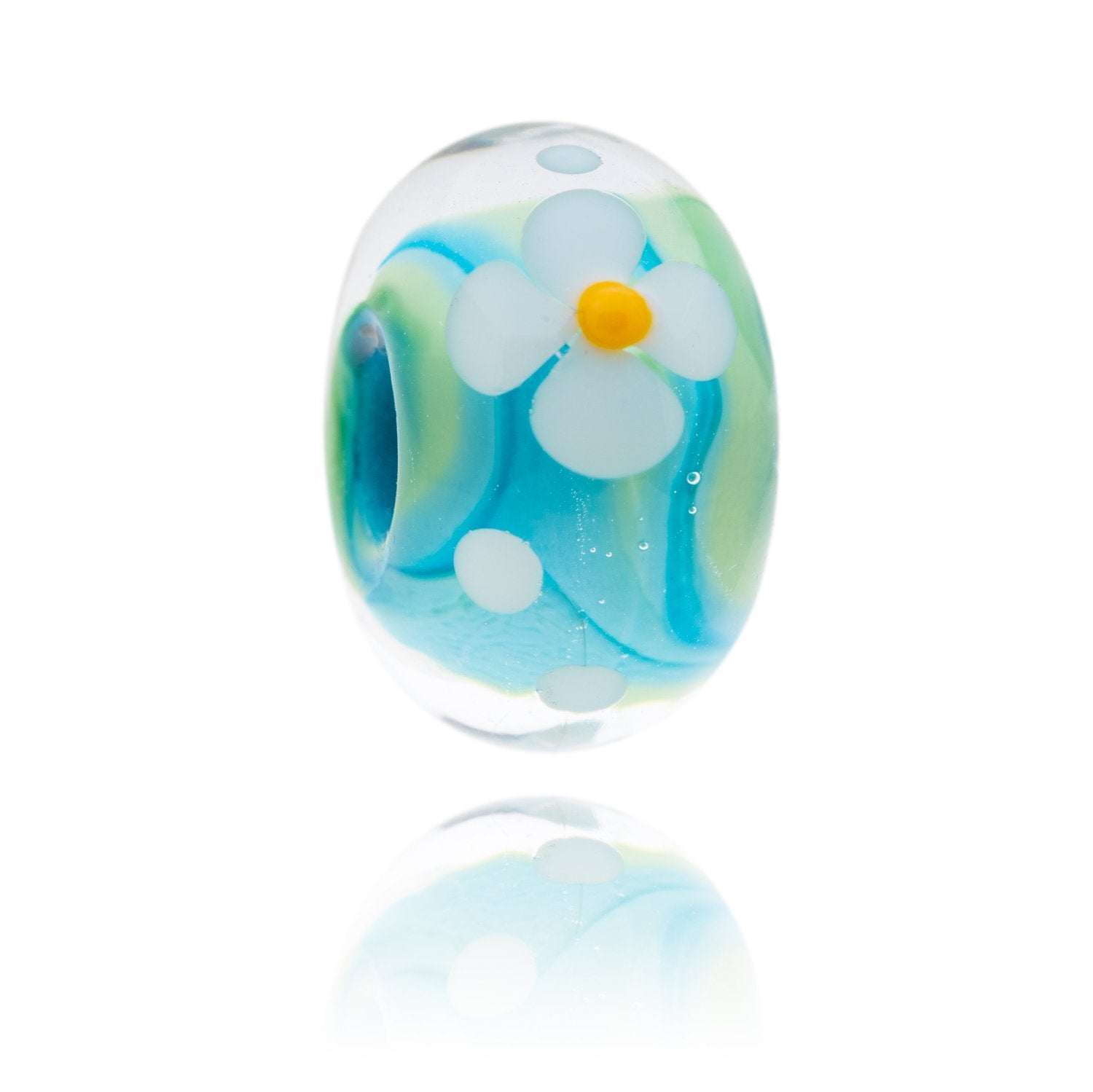 Blue and green swirly glass bead with a white flower decoration on the surface, representing Woolacombe beach in North Devon.