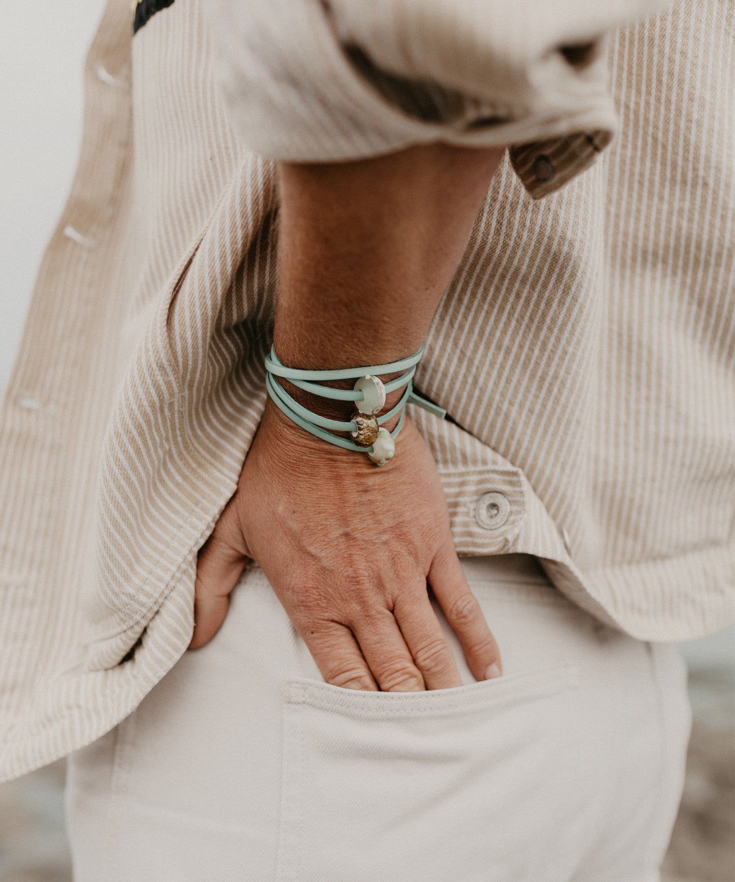 Aqua leather wrap bracelet with glass beads worn at the beach.