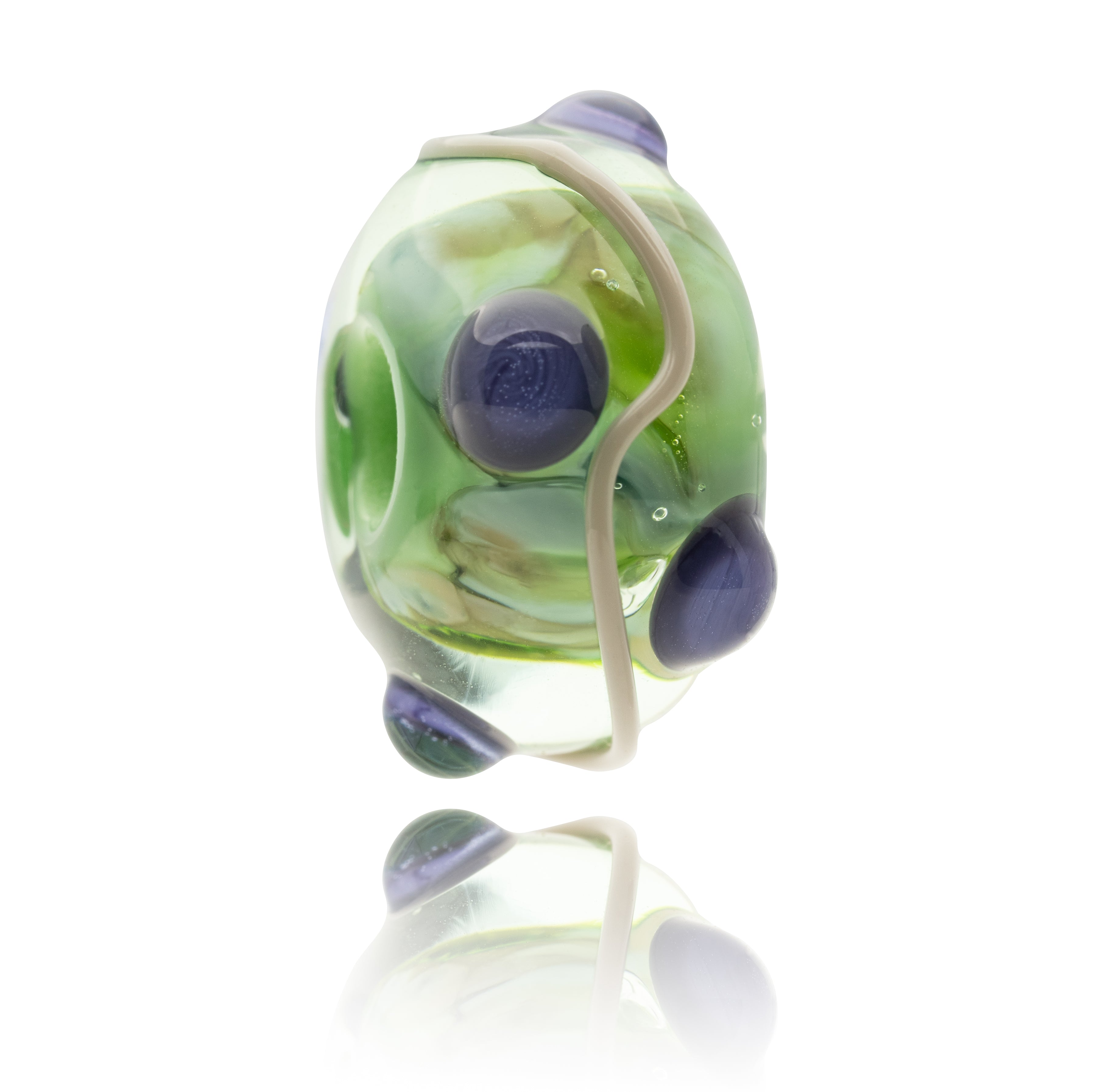 Glass bead charm with green, purple, and beige colours on a white background