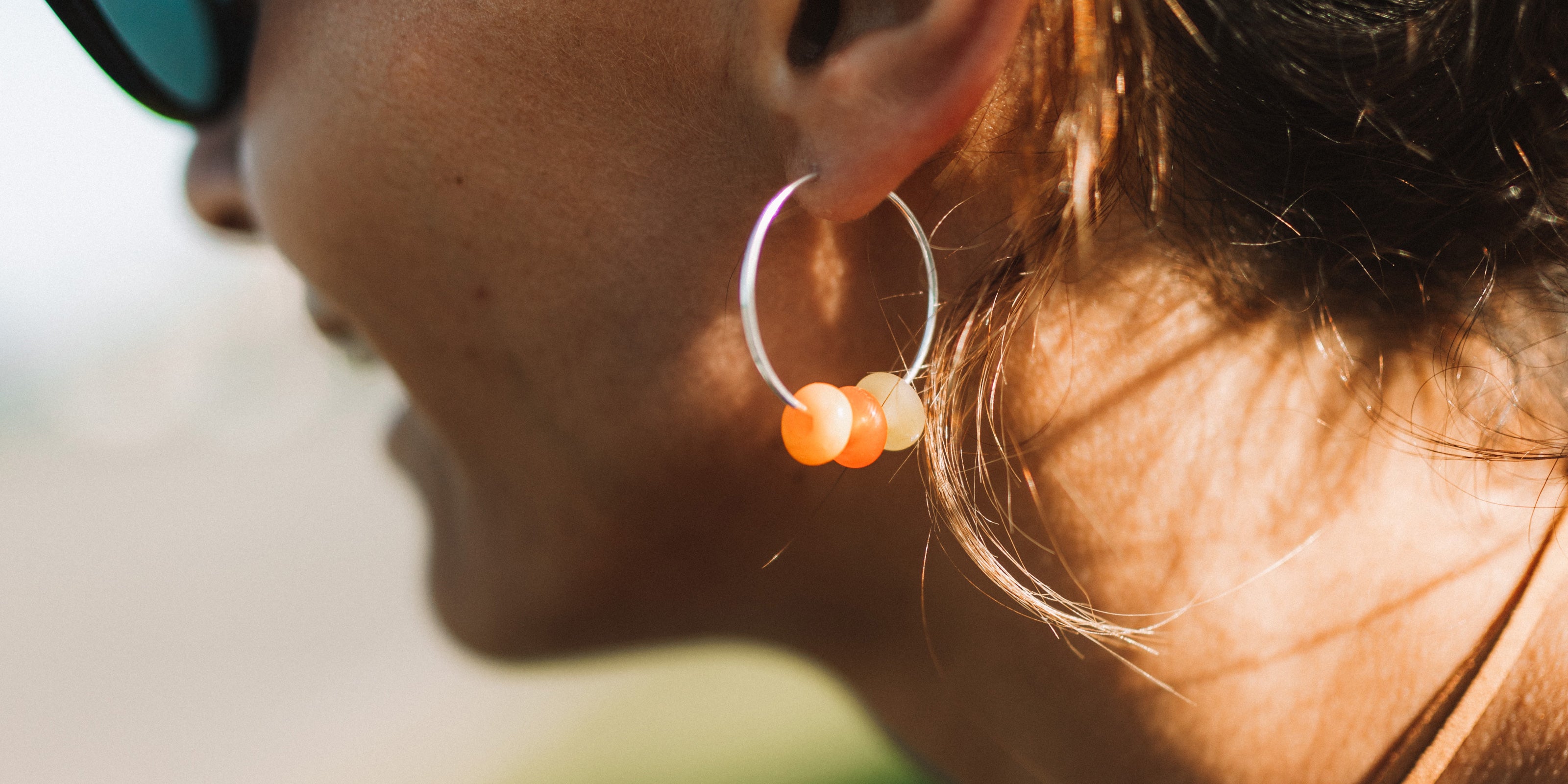 Orange and green beads on silver hoop earrings.