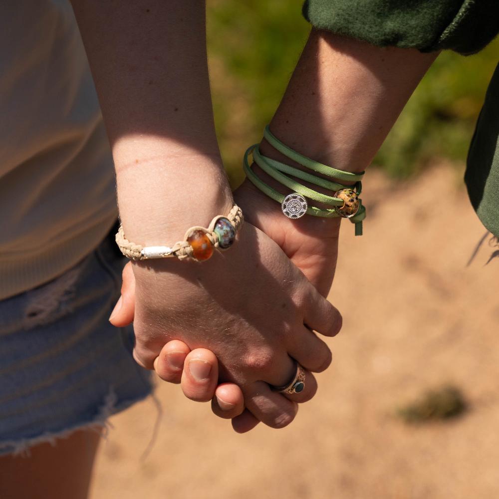 People holding hands walking in a national park, wearing bracelets with glass beads.