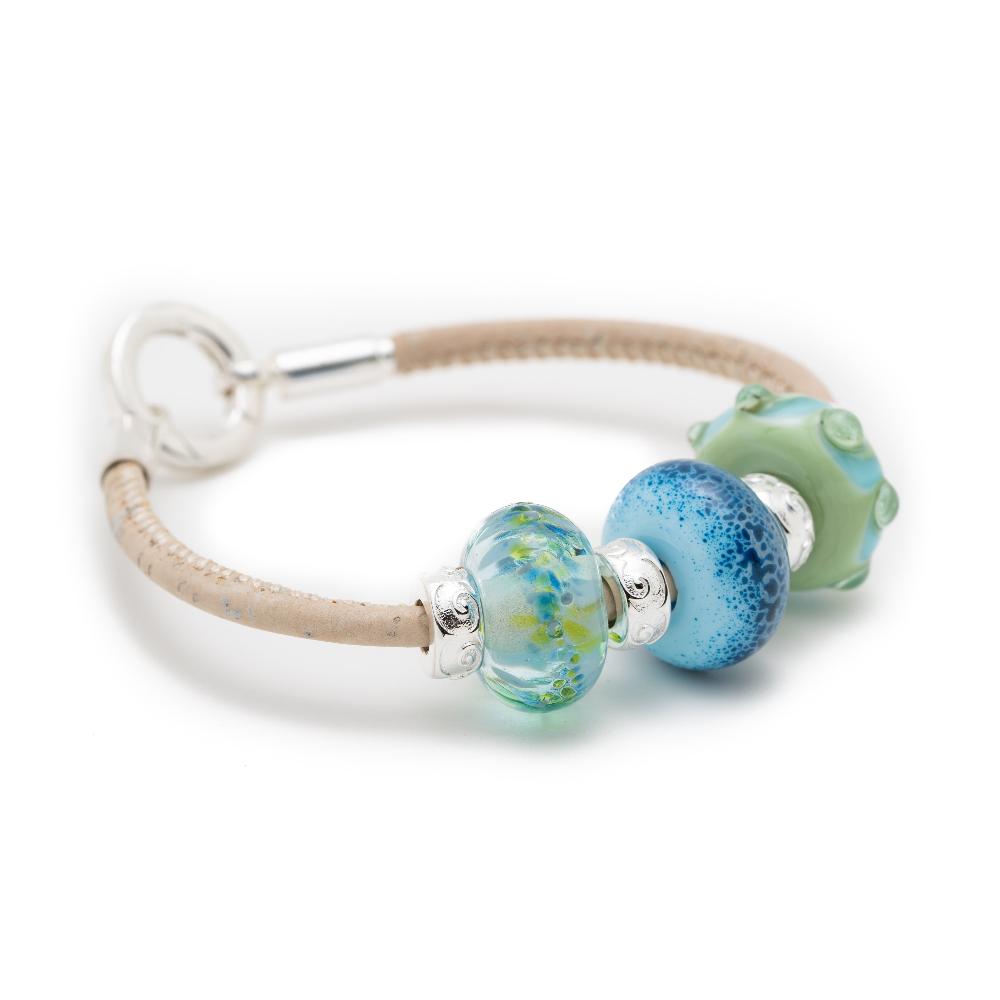 White cork bracelet with glass beads in greens, clear and blue shades with small silver beads in between.