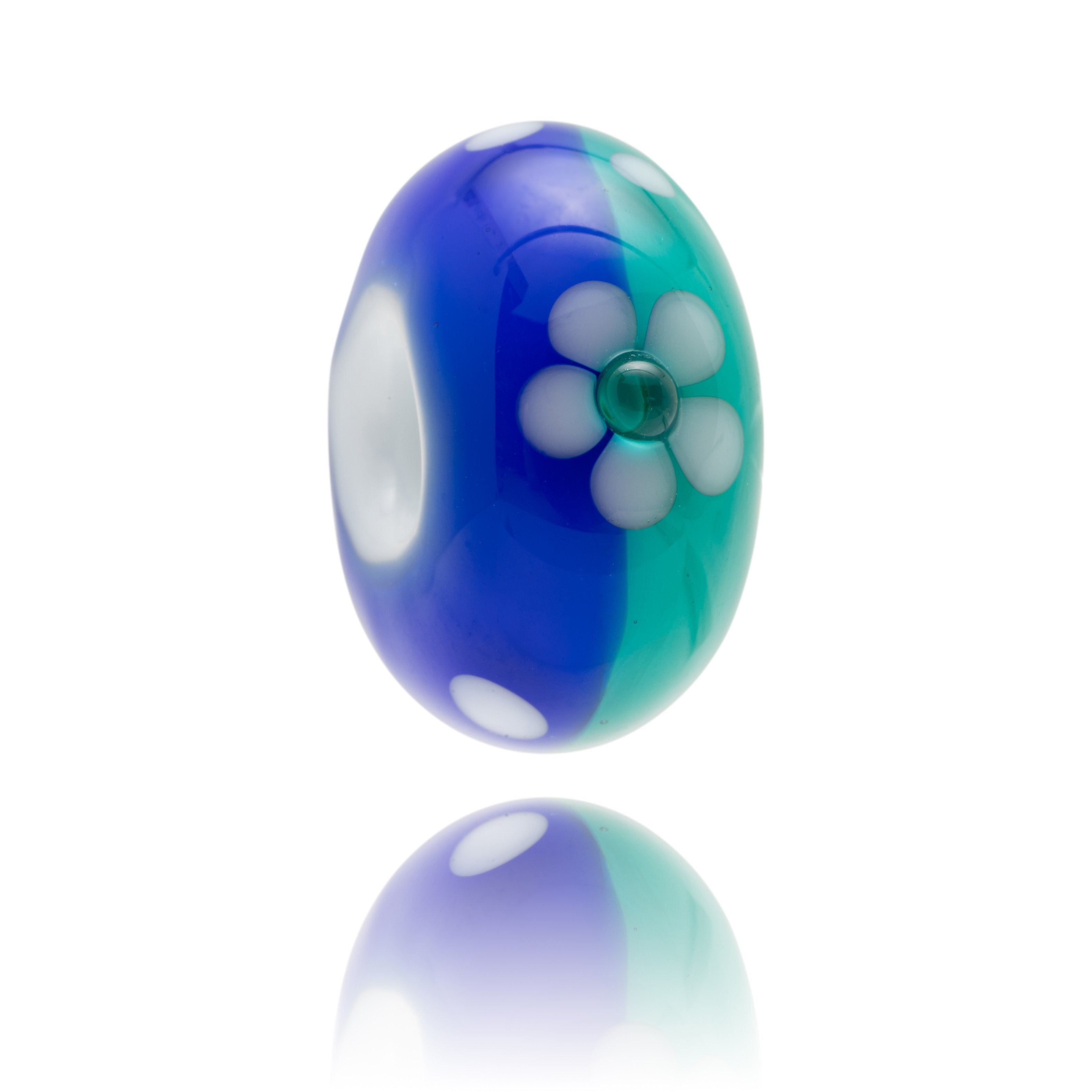 Blue and turquoise glass bead decorated with a white flower on the surface.