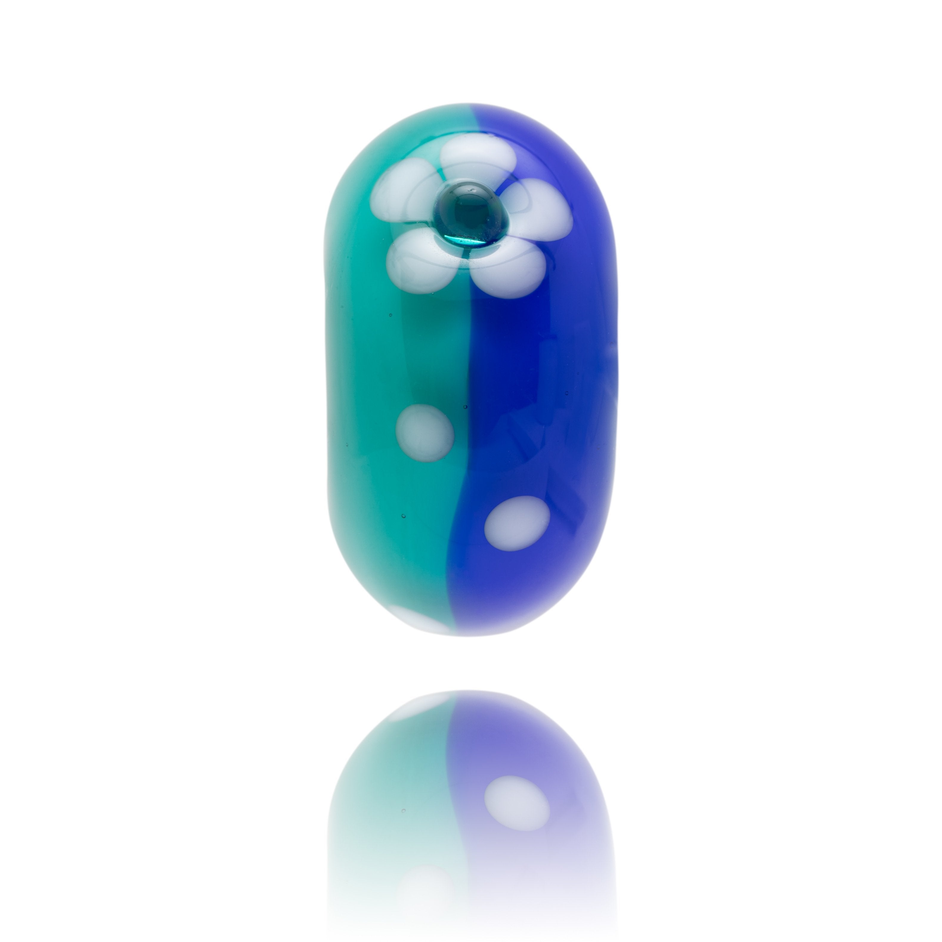 Blue and turquoise glass bead decorated with a white flower on the surface.