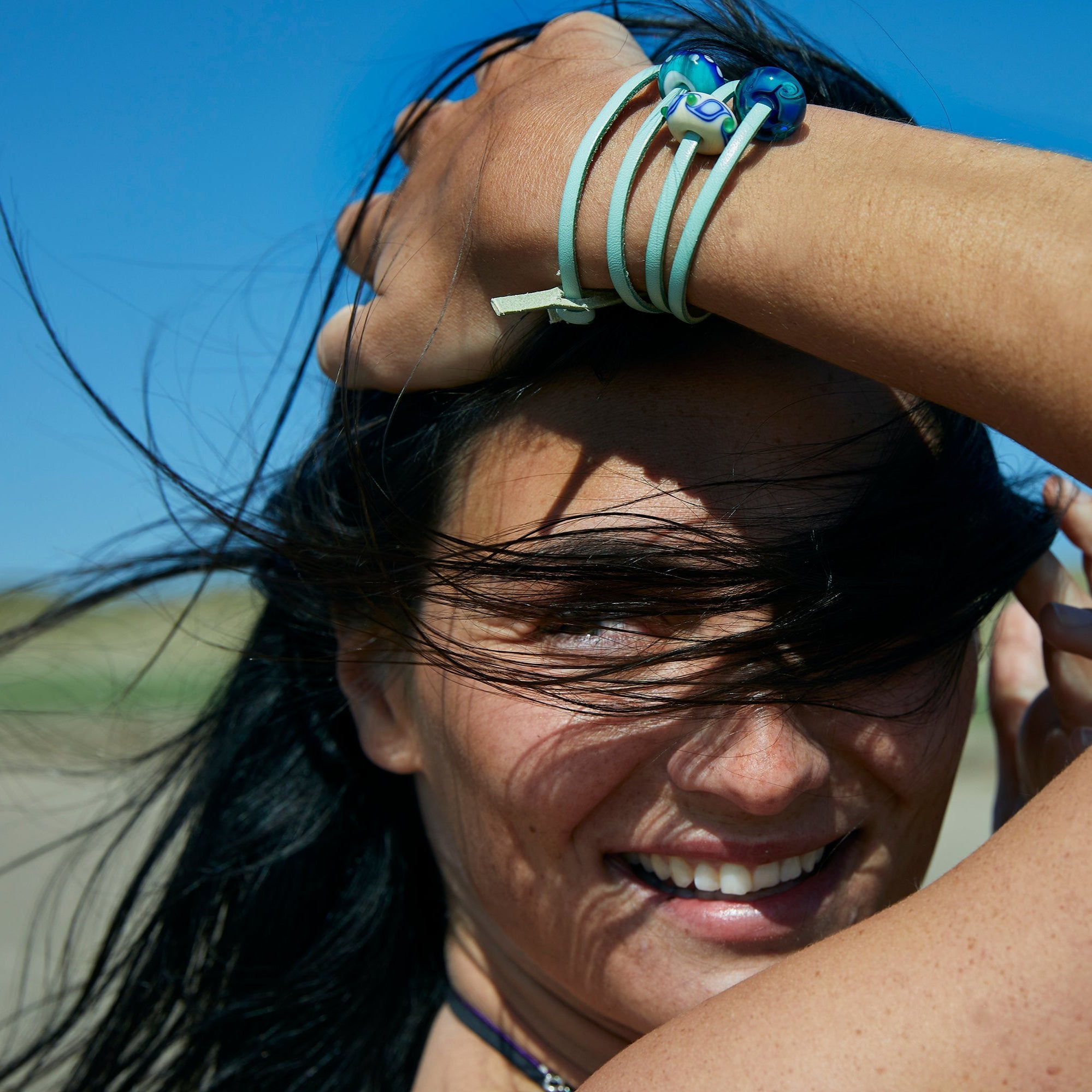 Bright blue surf inspired glass beads worn on turquoise leather wrap bracelet by woman at Crow Point in North Devon.