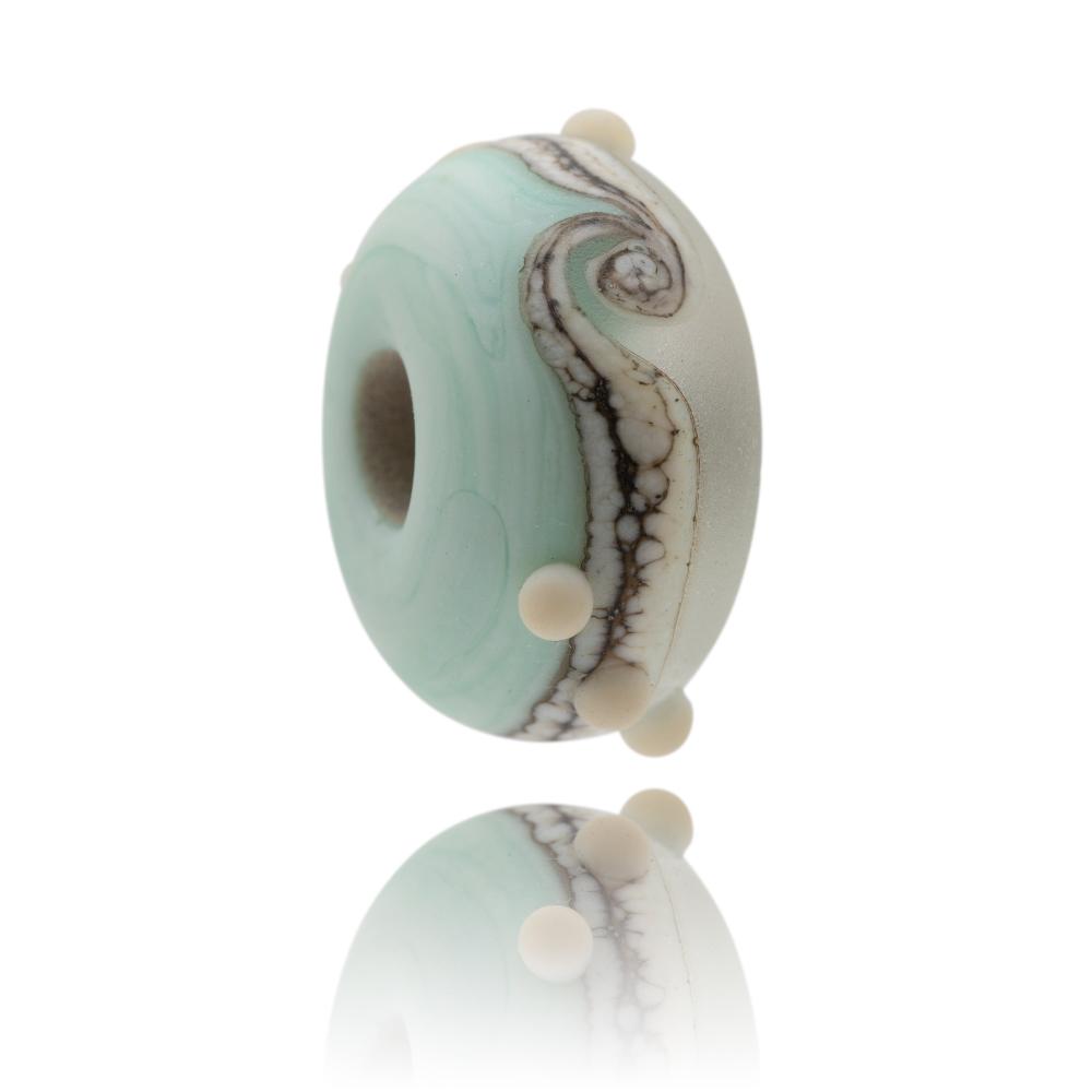 Green and clear frosted glass bead with a brown mottled swirl around the middle and little white surface dots, representing Lulworth Cove in Dorset.