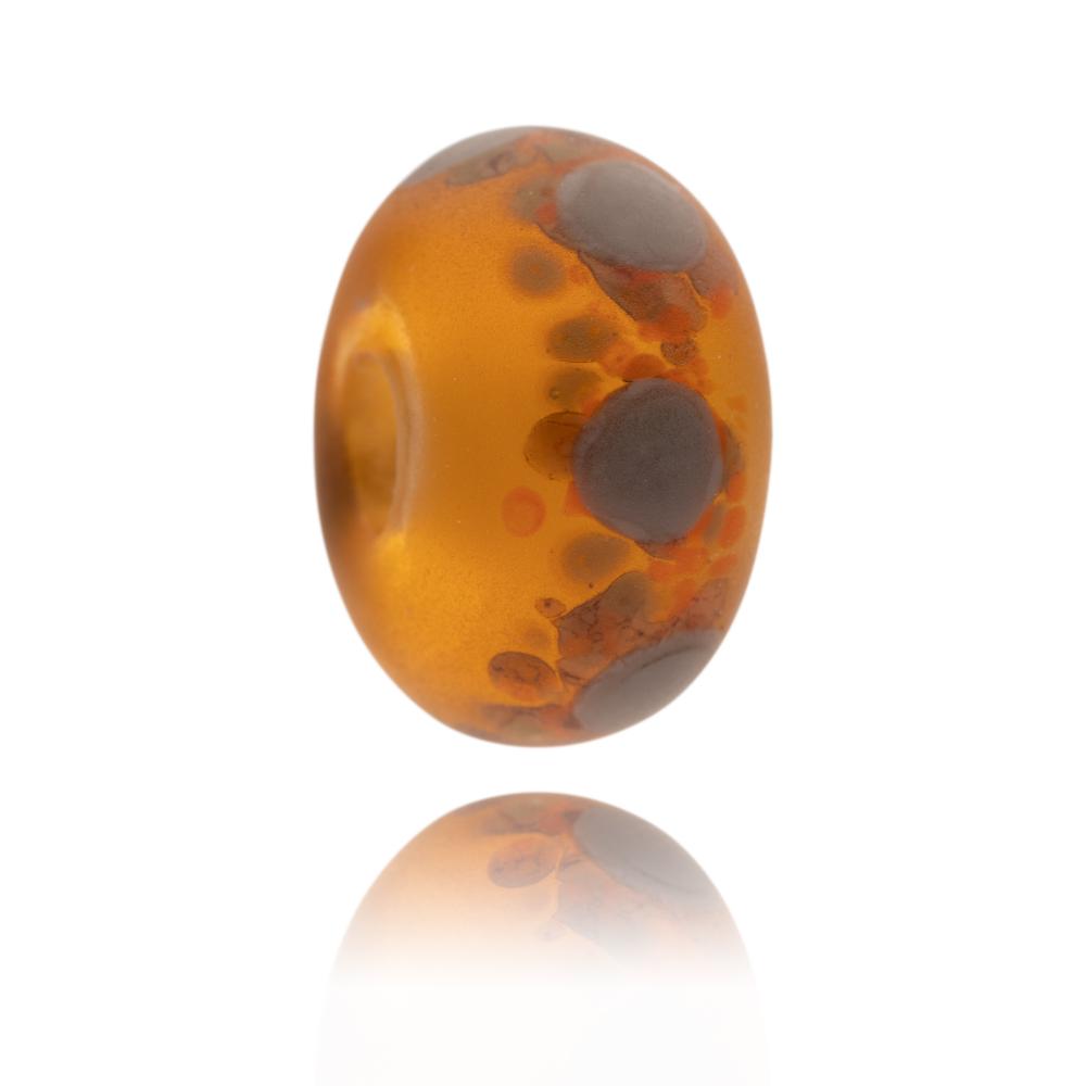 Dark amber transparent glass bead with brown and grey dots on the surface representing Dartmoor National Park.