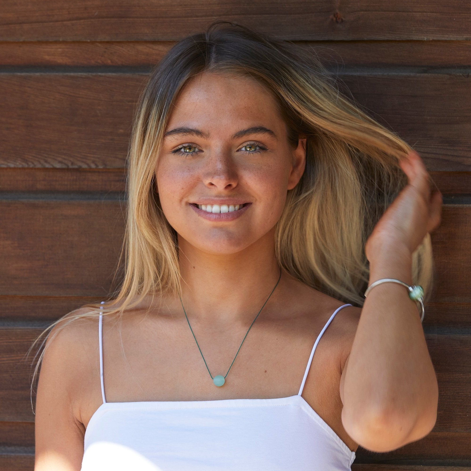 Mint green glass pebble necklace and Clovelly glass bead worn on silver bangle by pretty girl.