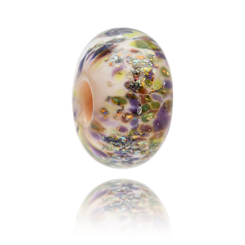 Cream glass bead with sparkle and glitter on the surface in purple, green and gold.