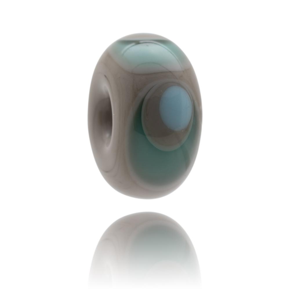 Dark grey glass bead with circular patterns of teal and blue glass representing Llangennith bay on the Gower in South Wales.