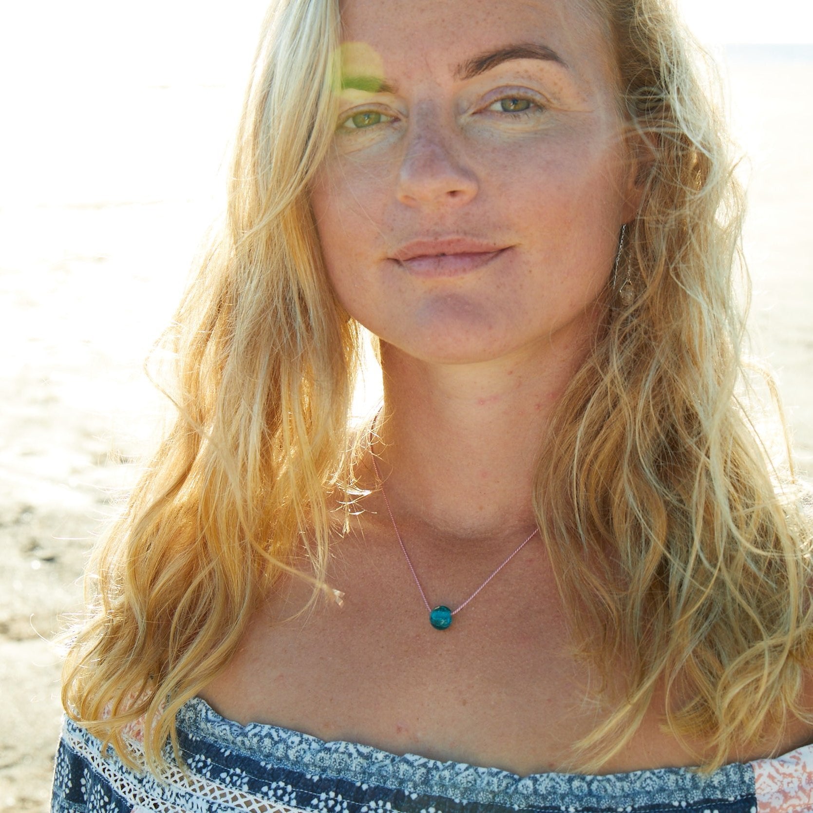 Plastic free North Deon charity pebble necklace worn by girl on beach.