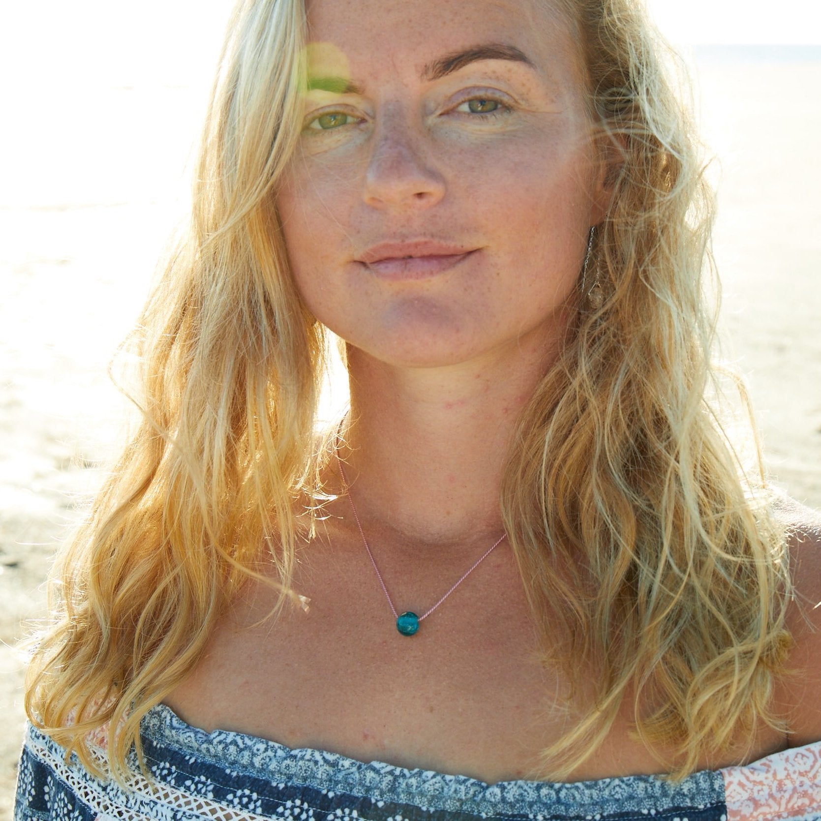 Woman wearing a glass pebble necklace at the beach.