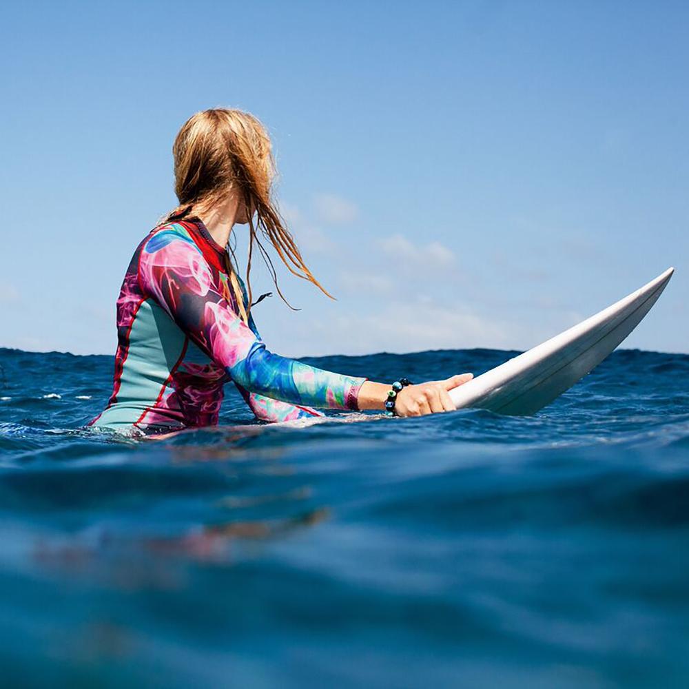 Girl on her surfboard sitting in the sea.