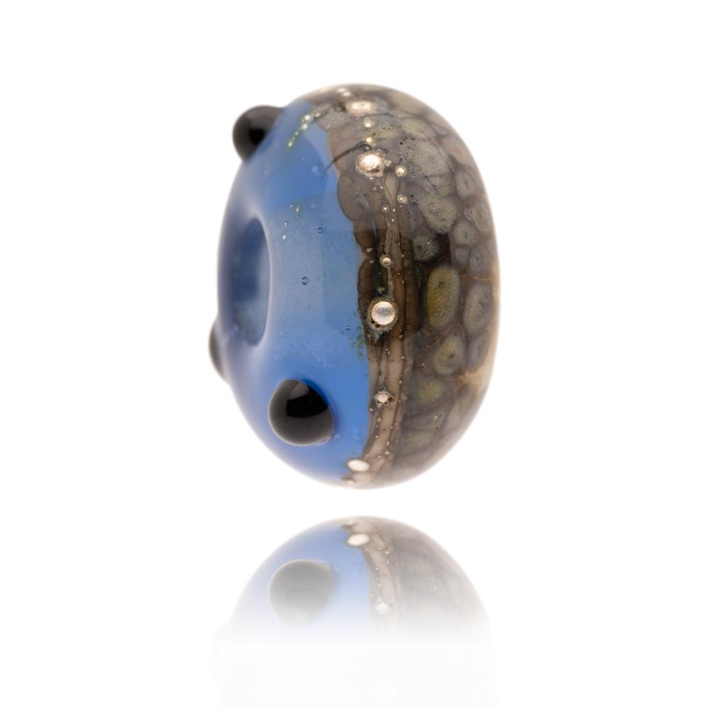 Blue and brown speckled glass bead with silver droplets and black dot patterns on the surface. Representing Southsea Beach in Hampshire, UK.