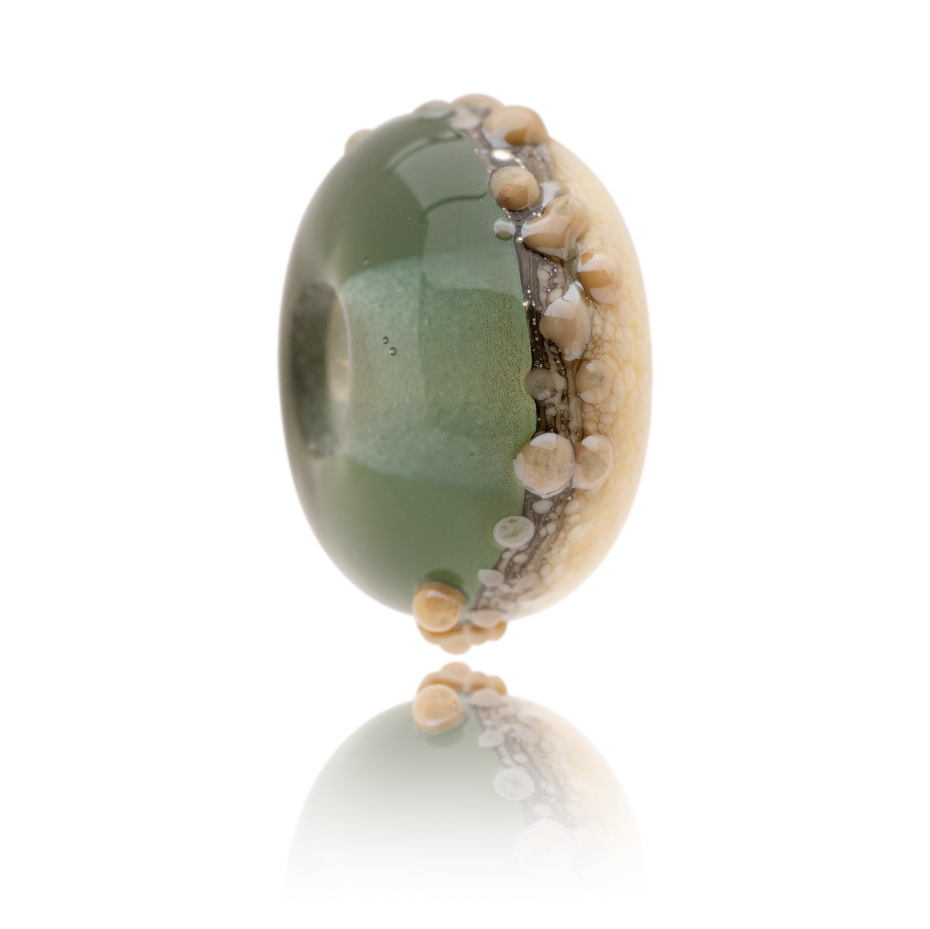 Green and ivory glass bead decorated with raised dots of brown glass, representing Worthing Beach in Sussex.