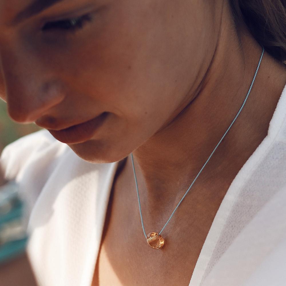 Woman wearing a amber glass pebble necklace.