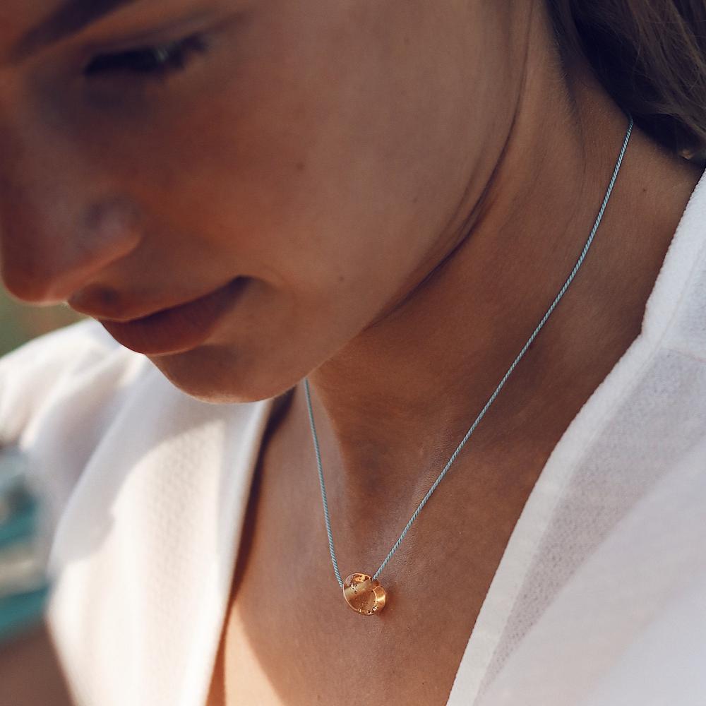 Woman wearing a amber glass pebble necklace.