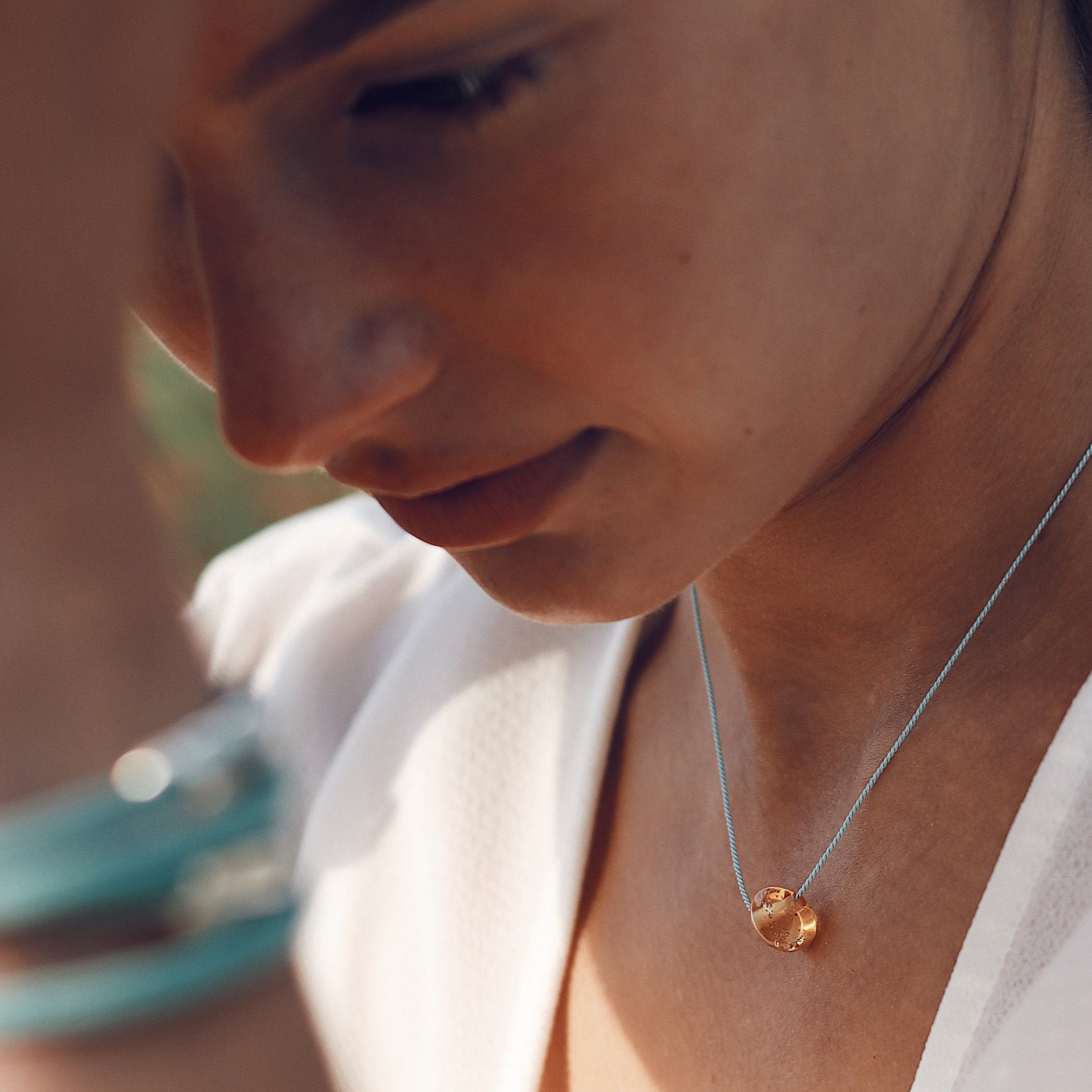 close up on woman earring cork bracelet and amber pebble necklace.