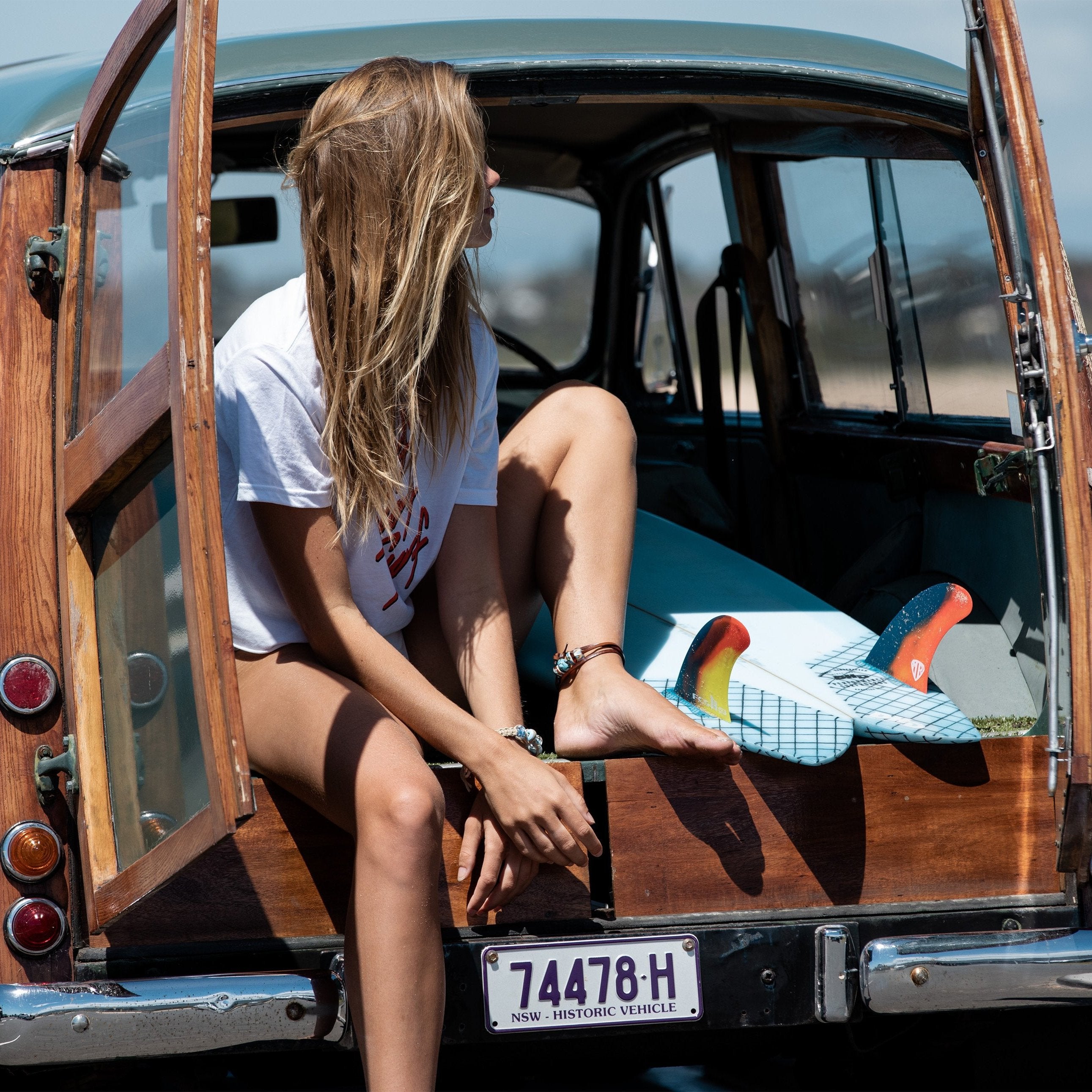 Surfer women wearing glass bead cord bracelet and brown leather wrap anklet.