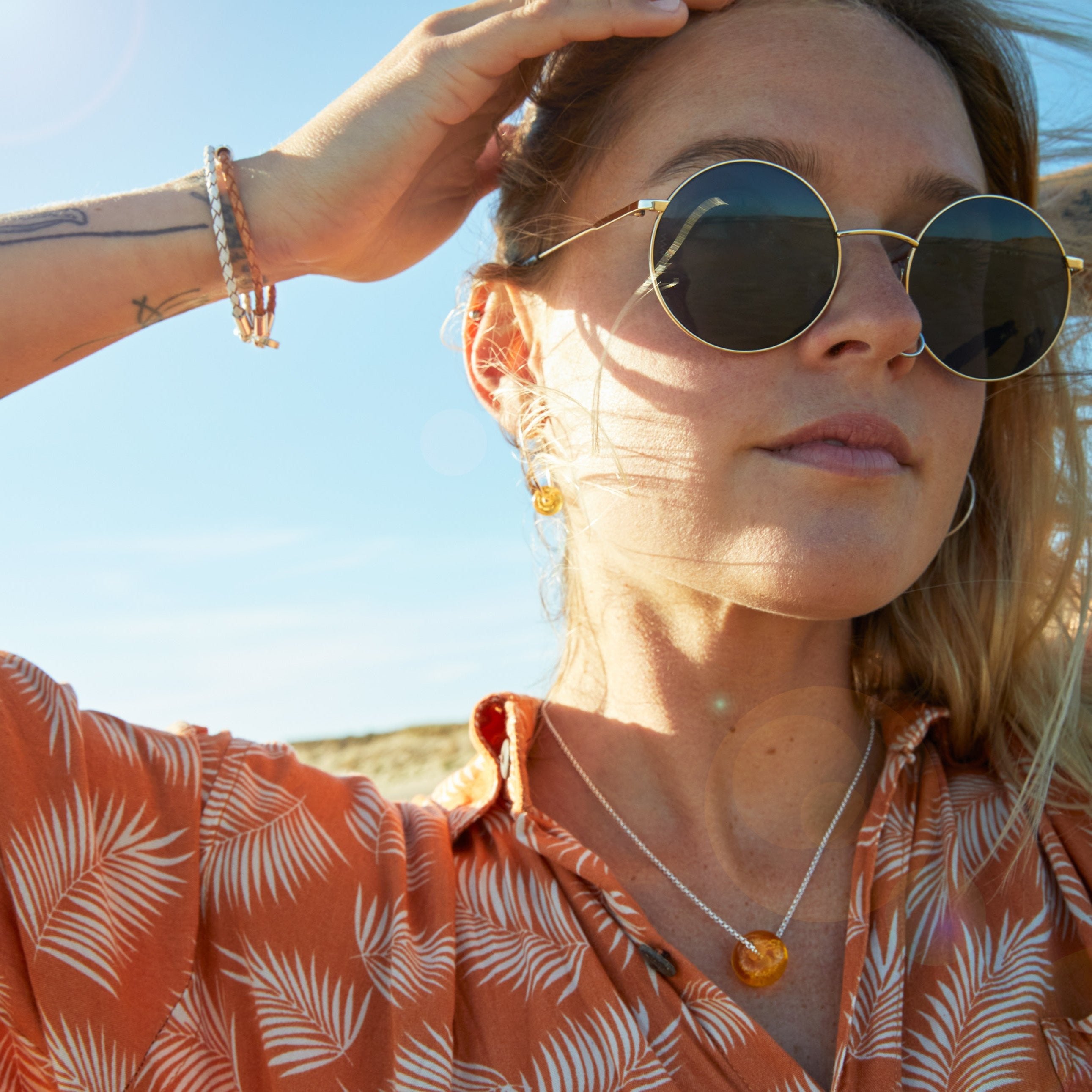 Woman wearing Nalu sand bead necklace, earrings and bracelets at the beach.