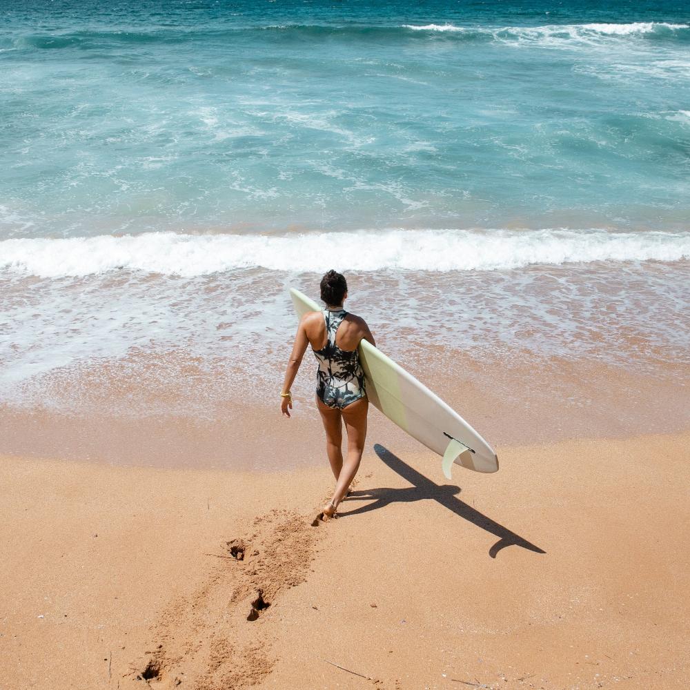 Surfer walking in the sea carrying a board.