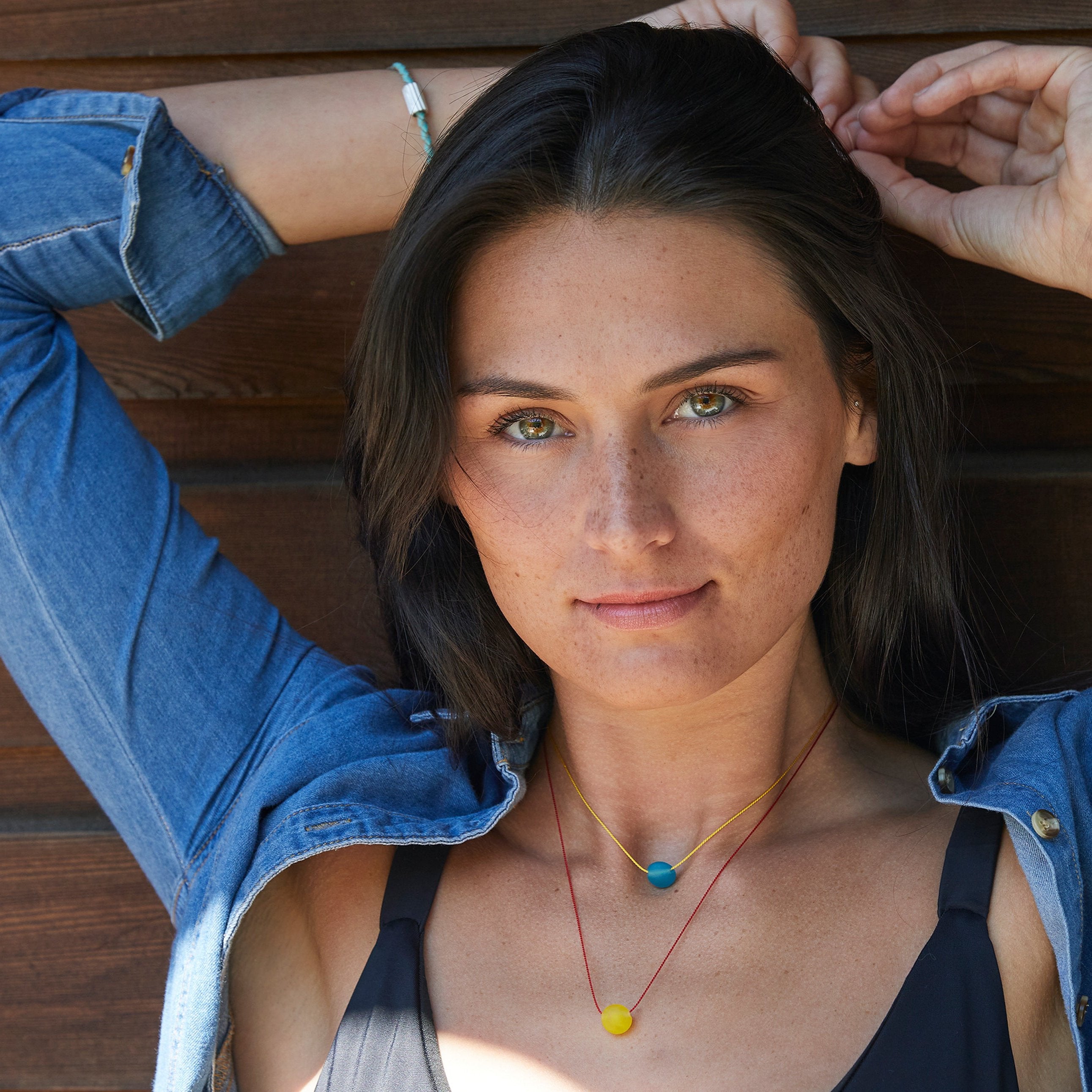 Girl in denim jacket wearing colourful glass bead necklaces in layers.